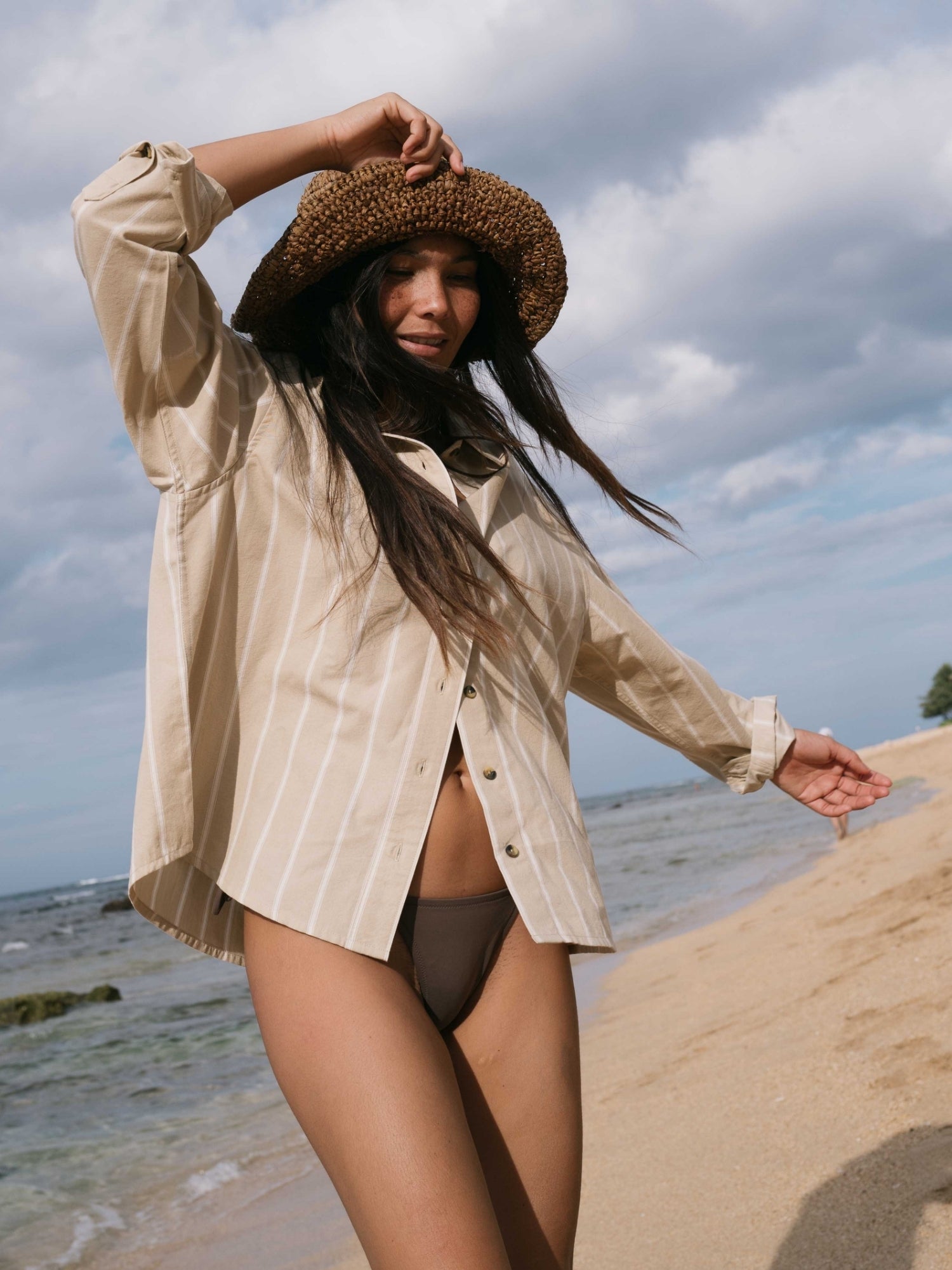 Fashion model dressed in adventure-inspired outfit featuring a stylish hat, emphasizing beauty and fashion in an outdoor setting.