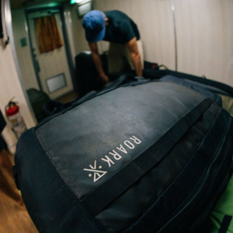 Mochila Roark Accomplice Mule 45L negra con el logo a la vista, escena lifestyle