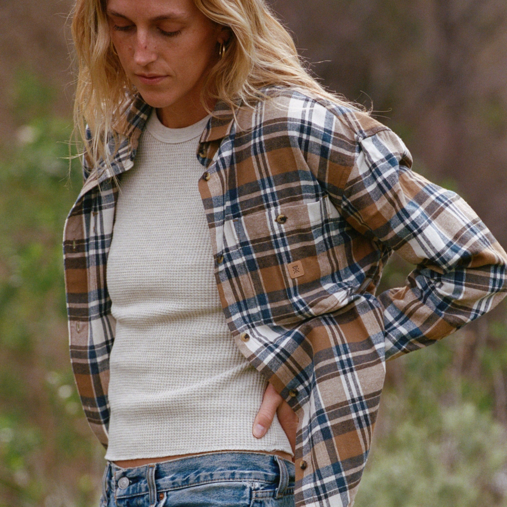 Long sleeve flannel in amberley light plaid over denim jeans, emphasizing an adventurous travel and outdoor style.