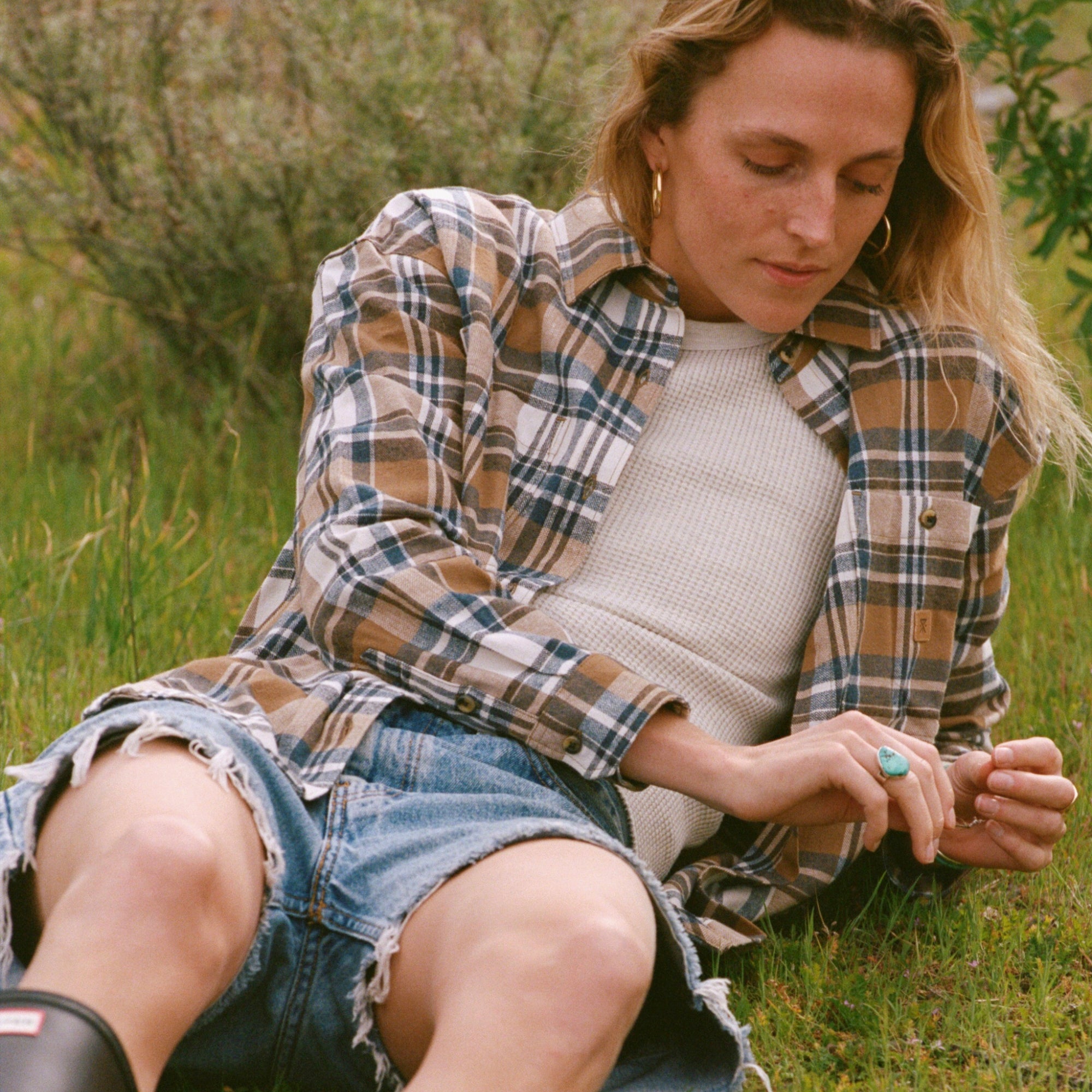 Blonde man in tartan plaid Amberley light long sleeve flannel, paired with denim, embodying Roark's adventurous outdoor spirit.