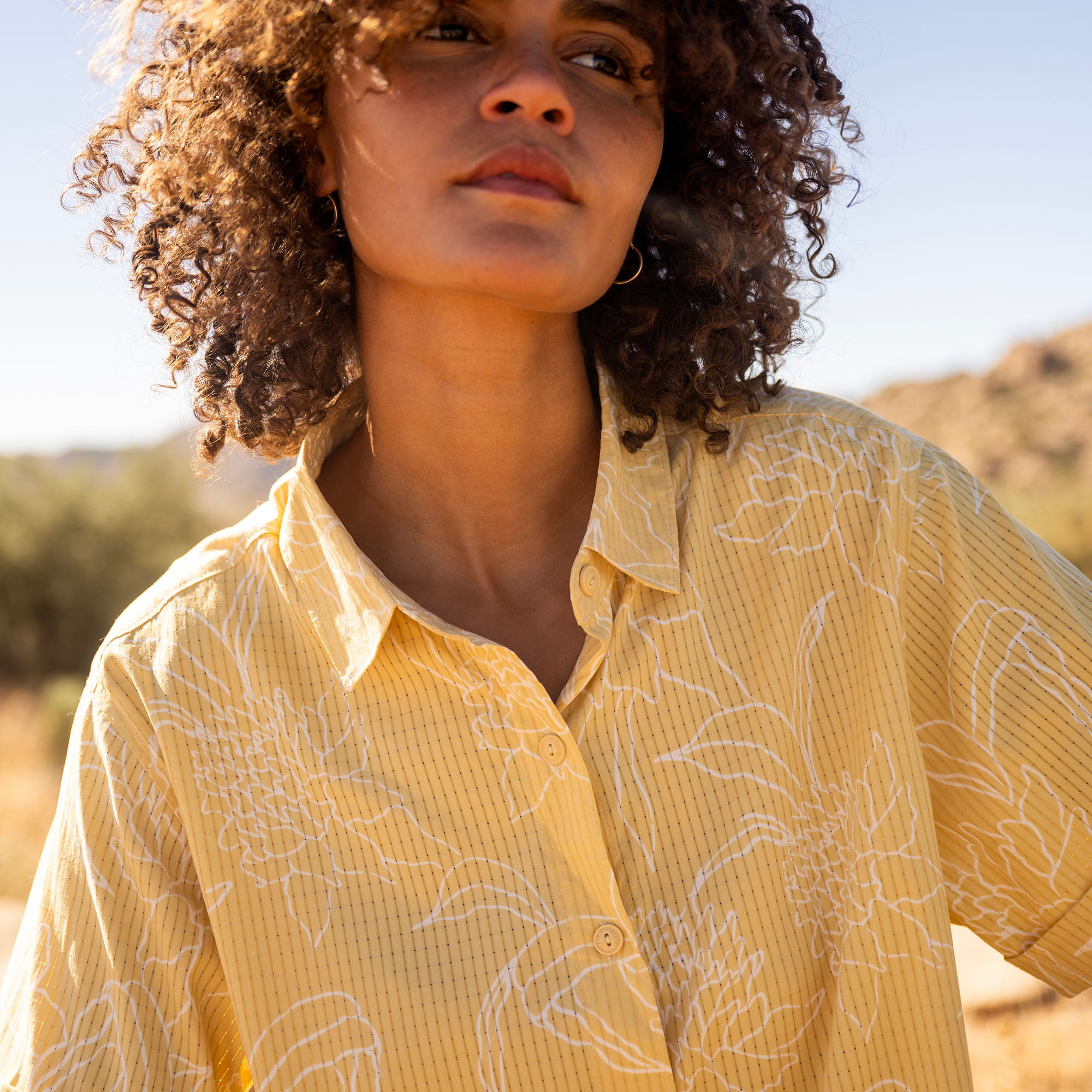 Bless Up cropped button-up shirt in yellow with white abstract pattern worn outdoors in natural sunlight