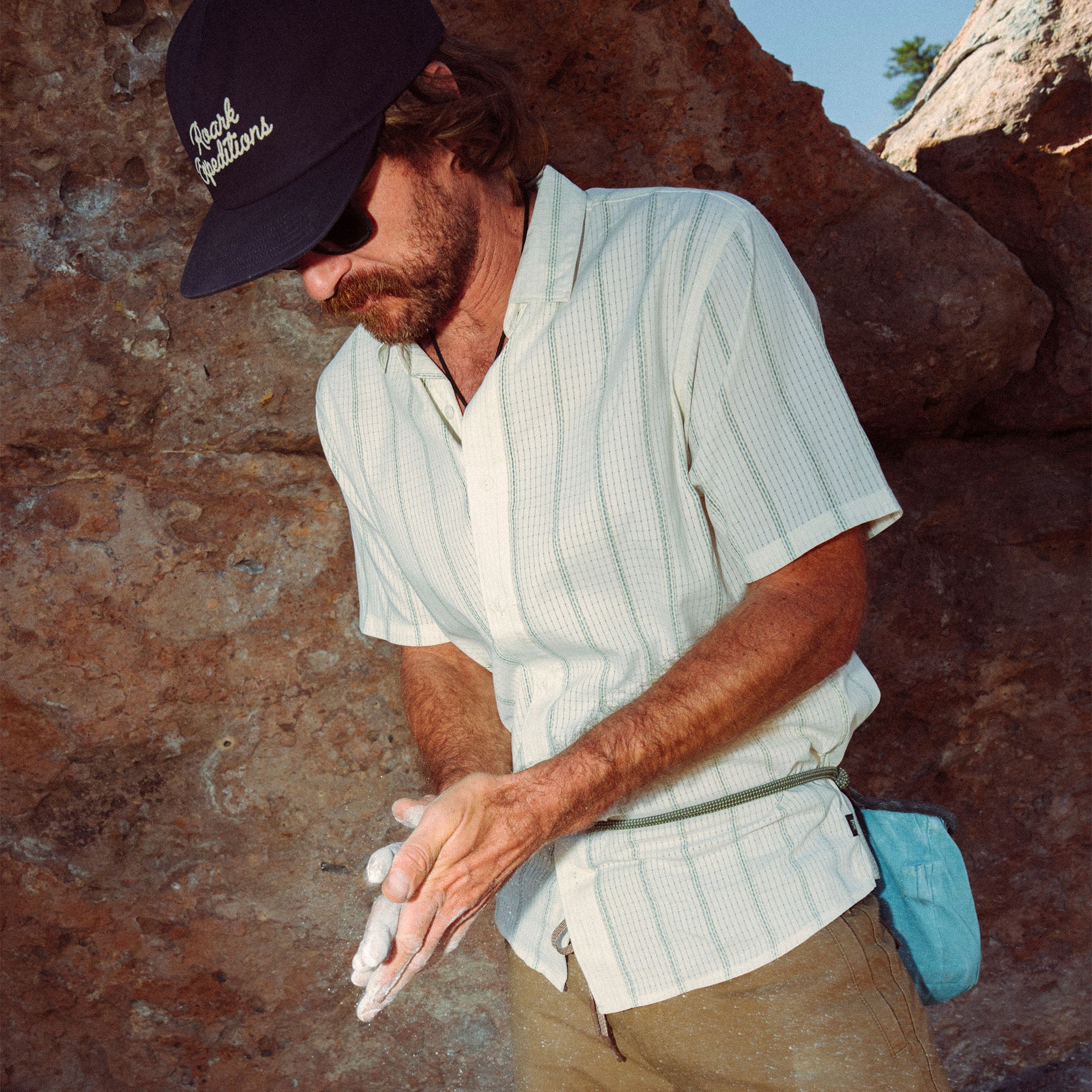 Model wearing a Bless Up shirt from Roark's Fall 2025 collection, styled with a casual cap, emphasizing outdoor and adventure-ready apparel.