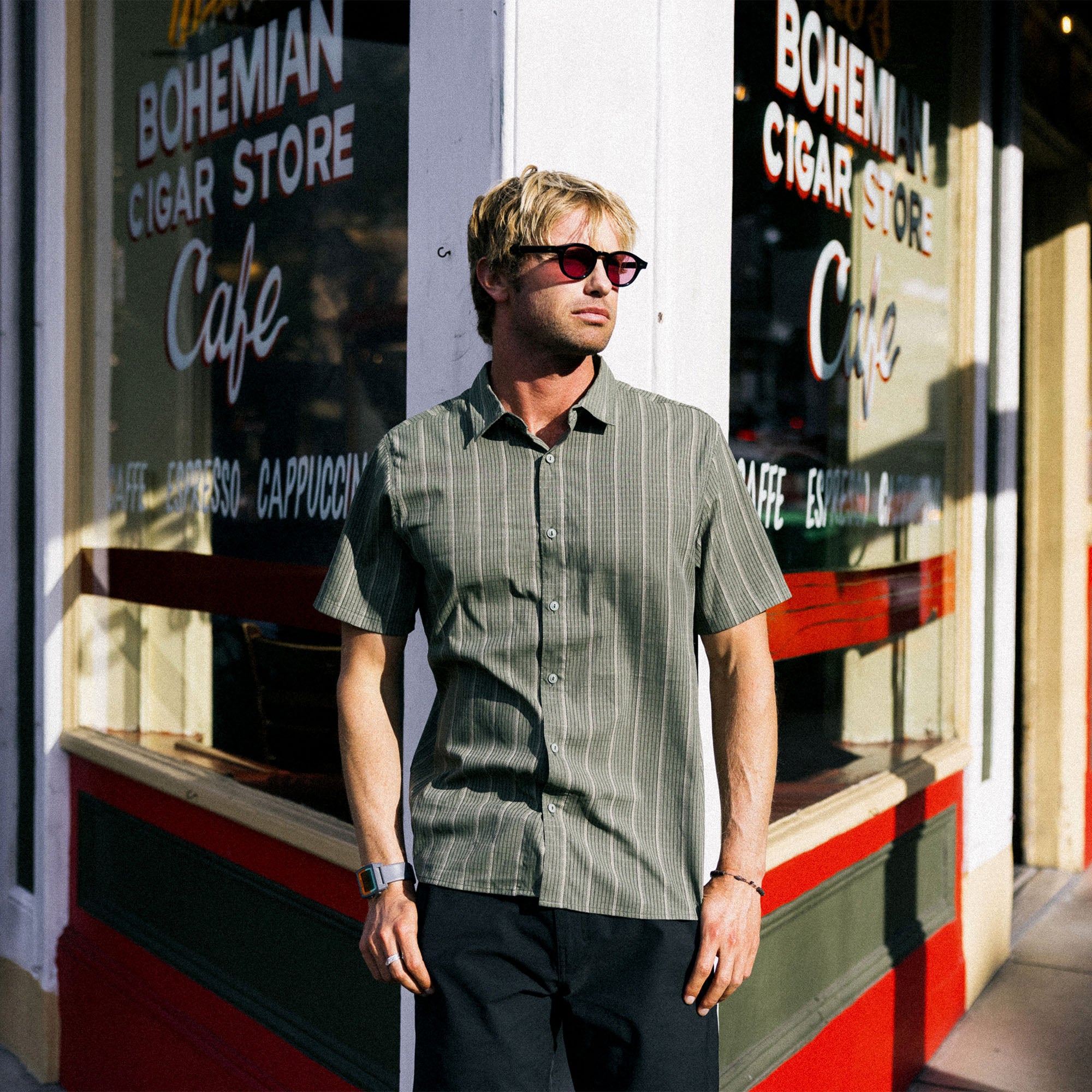 Adventure-ready man wearing Roark's Bless Up dress shirt with visible collar and pocket details, complemented by stylish eyewear, embodying the spirit of travel and outdoor exploration.