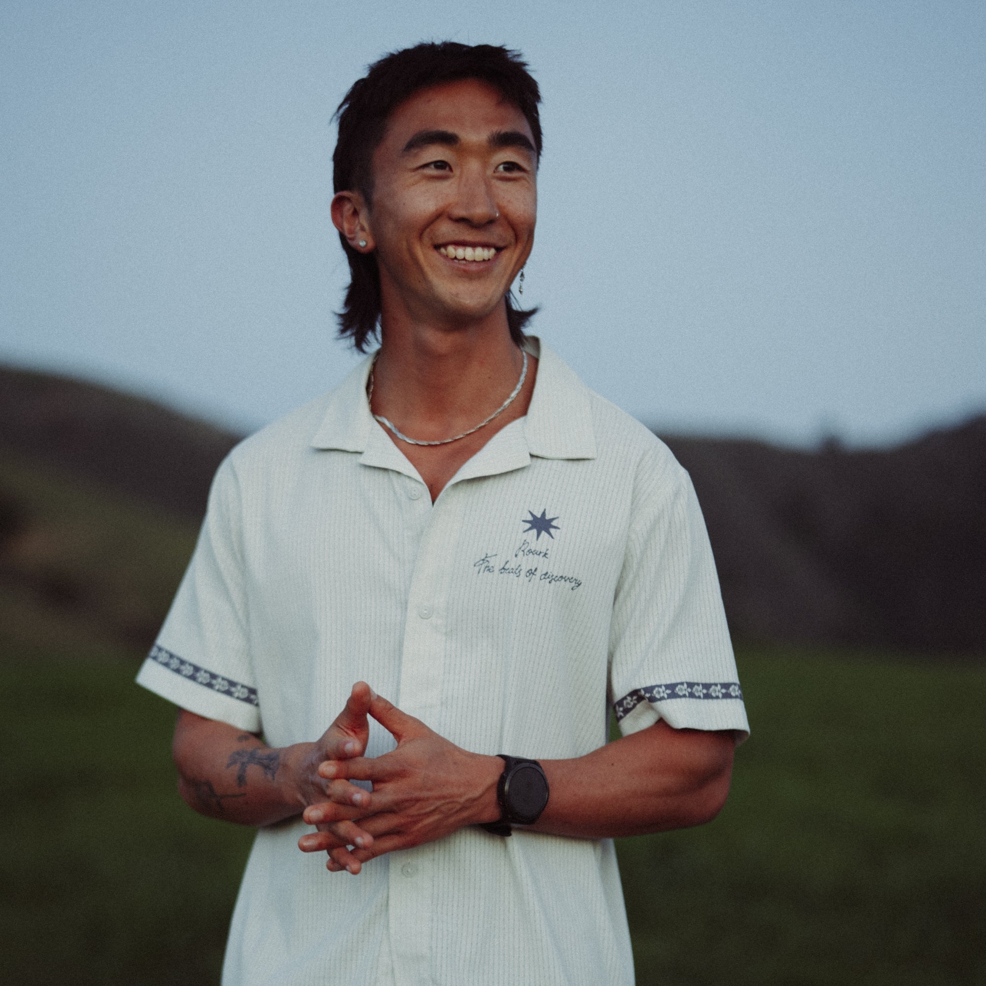 Happy hiker smiling on trail wearing a Roark Bless Up SP26 shirt, showcasing outdoor happiness and adventure