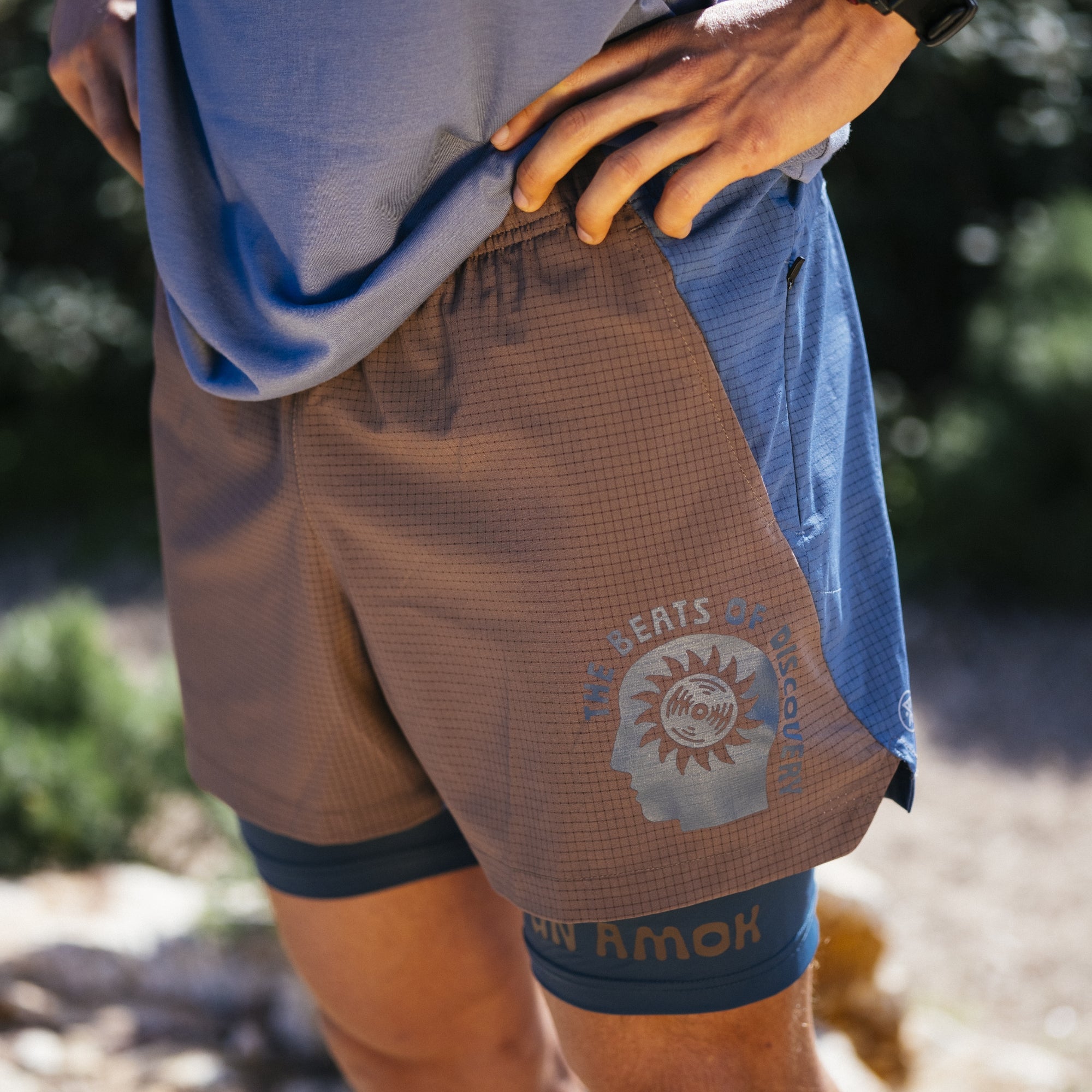 Man wearing Roark active shorts and shirt ensemble, styled for adventure, posed in an outdoor setting, epitomizing travel and exploration.