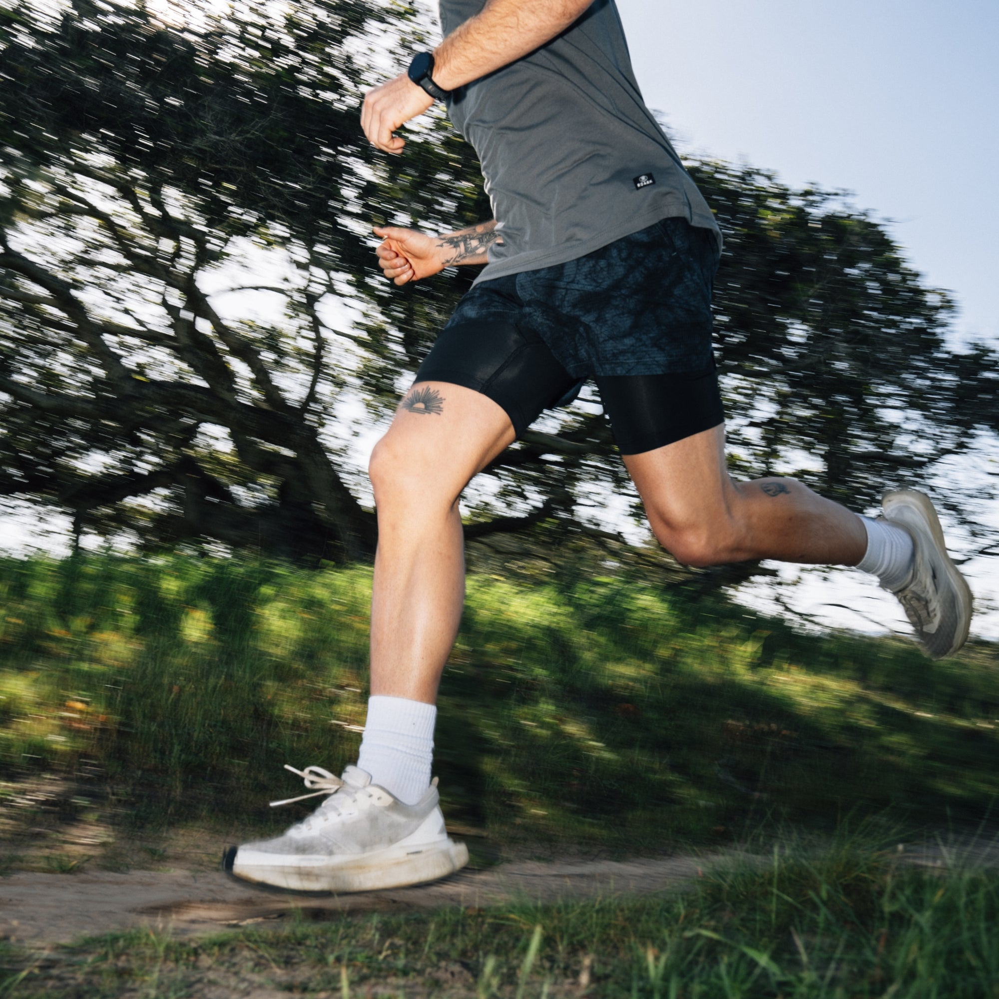 Man wearing Roark Bommer 3.5 shorts standing in an outdoor setting, showcasing the fit from thigh to calf with visible footwear.