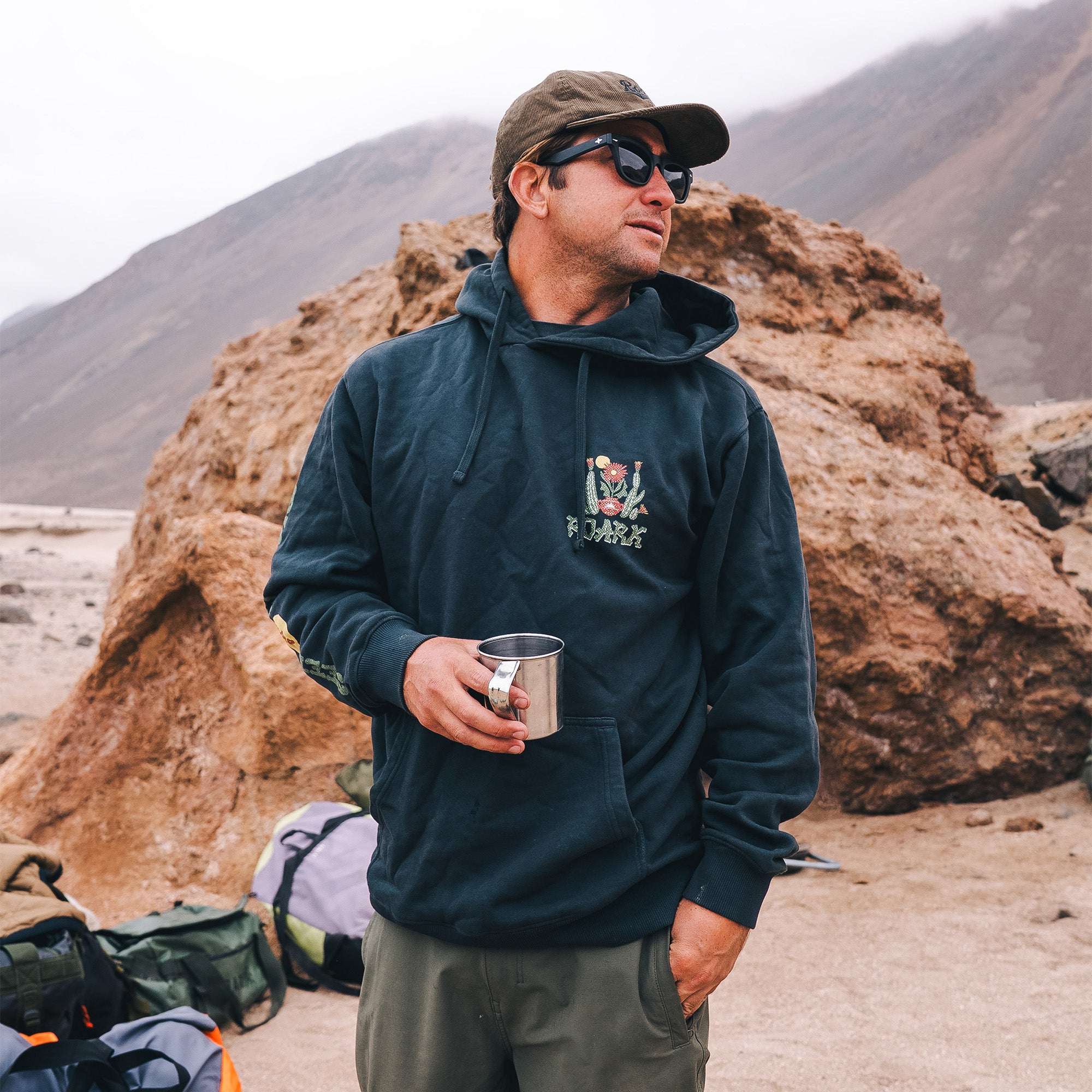 Adventurous person wearing Roark's Cactus Garden Fleece hoodie, styled with sunglasses for an outdoor exploration.