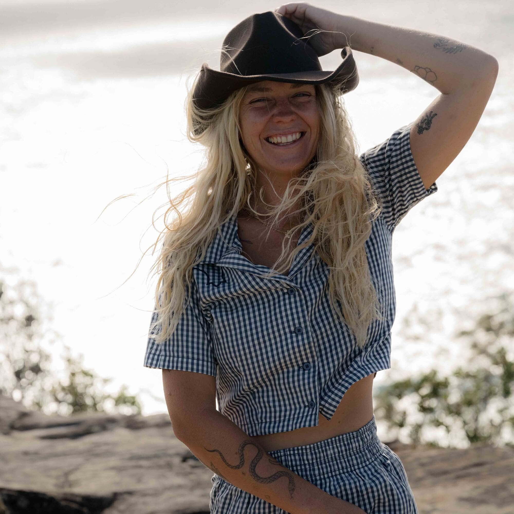 Man in a plaid camp shirt and summer hat, embodying Roark's adventure and travel style.