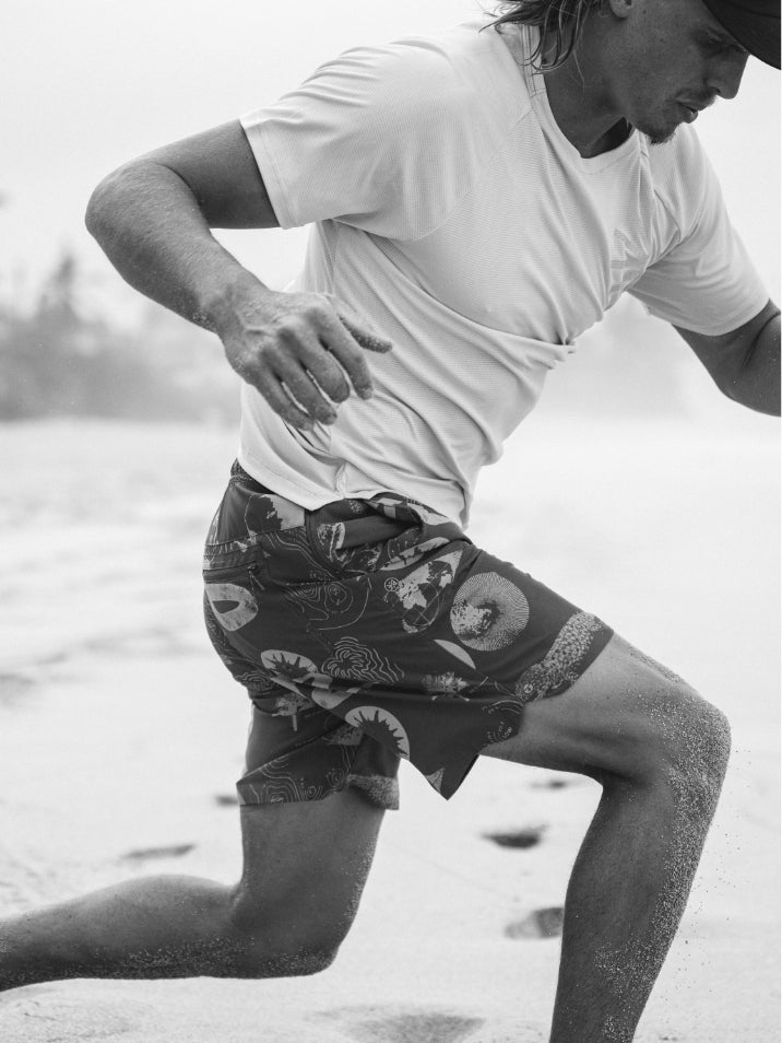 Active man in black boardshorts running on a summer beach, showcasing Roark's adventure-ready style
