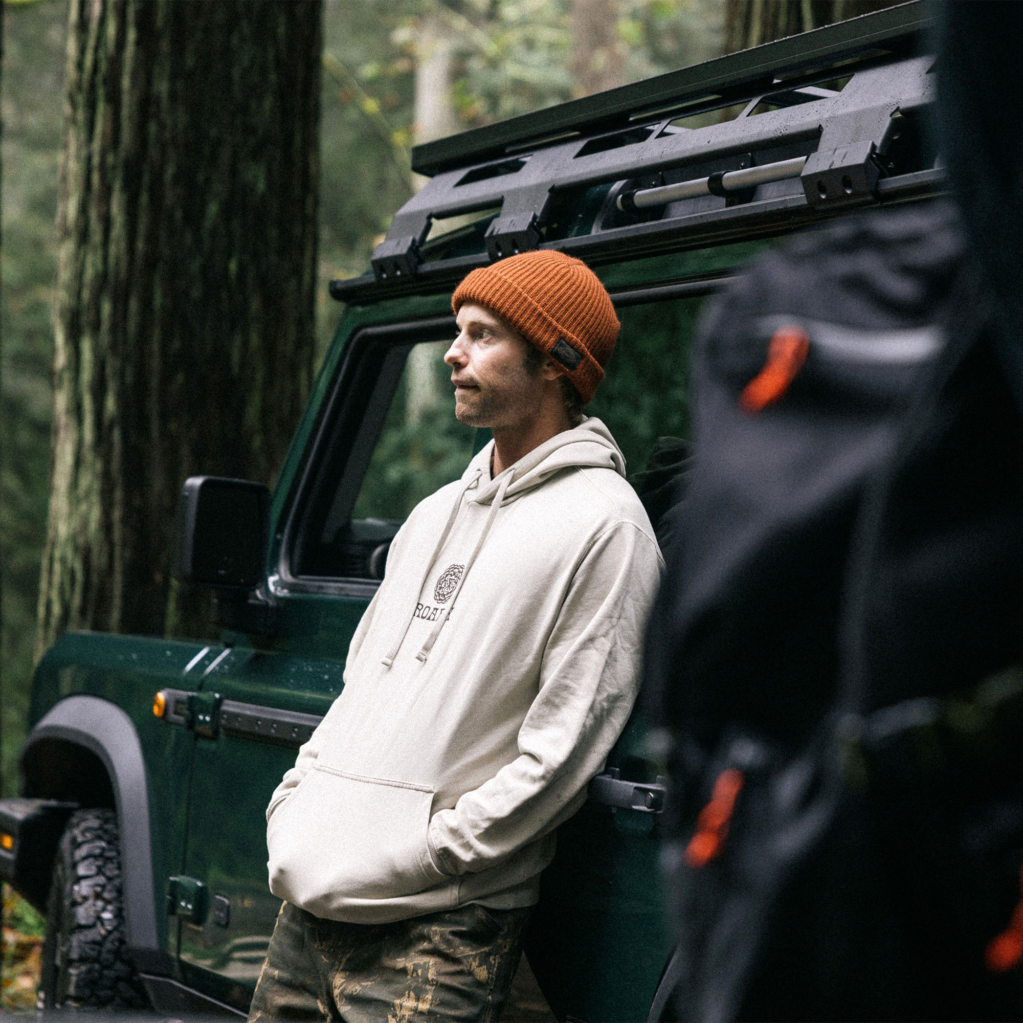 Adventure-ready man wearing Roark's Cone Collectors Fleece jacket with hood and knit beanie in a rugged outdoor setting.