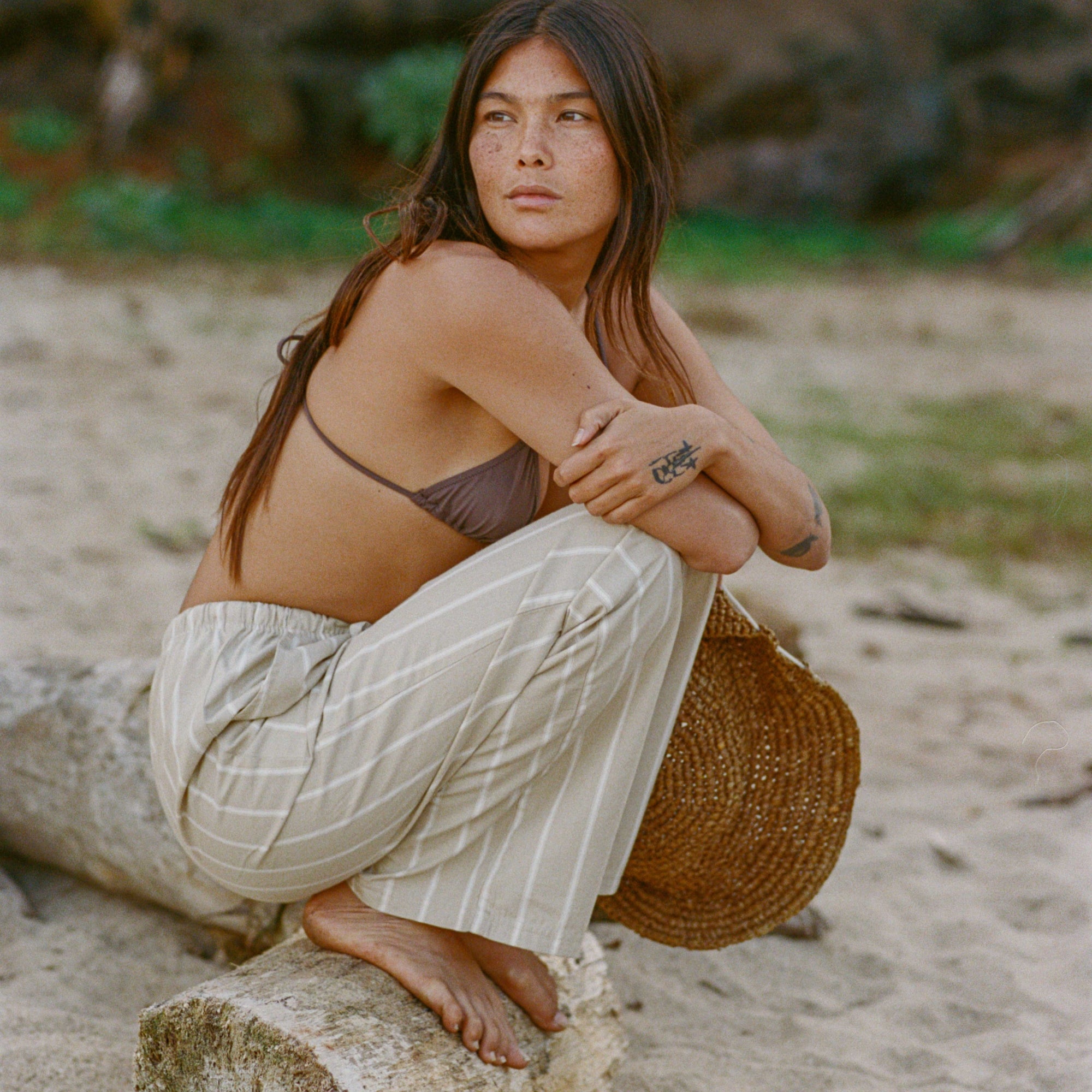 Photo shoot in a natural setting featuring a barefoot person with long hair, model wearing Costa Pants from Roark's Spring collection, showcasing a blend of adventure and style.