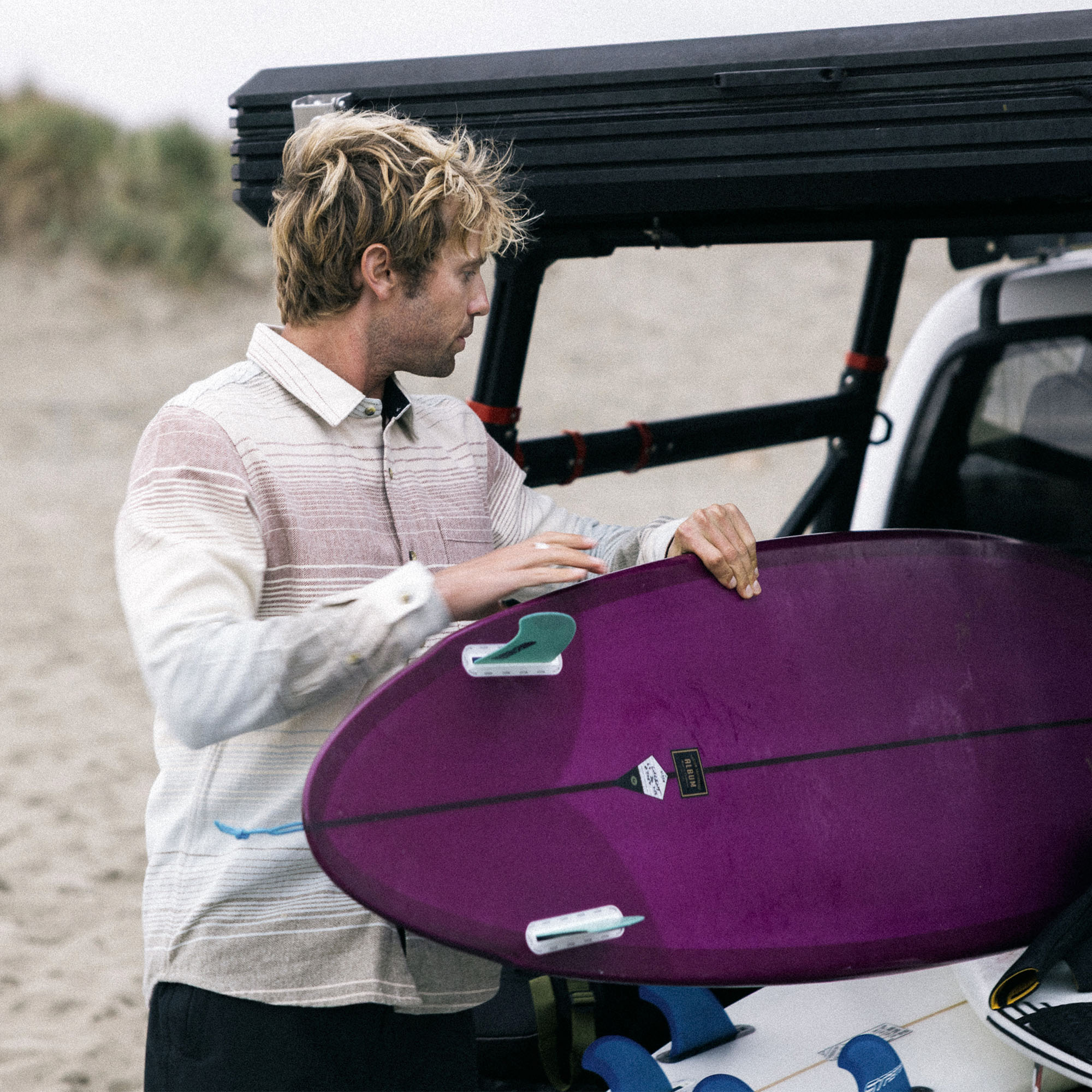 Surfboard and surfing gear laid out on an organic cotton flannel, embodying Roark's commitment to adventure and sustainable outdoor equipment.