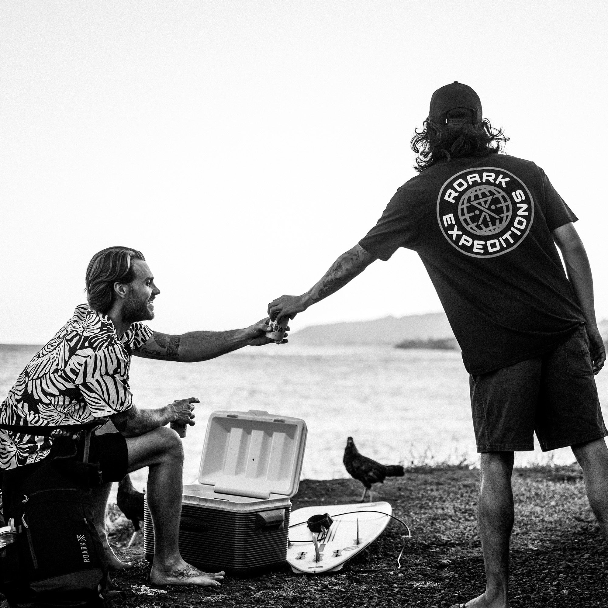Black and white photo of a person having fun at the beach, capturing the adventurous and carefree spirit perfect for Roark's Division Premium Tee SP26 wearer.