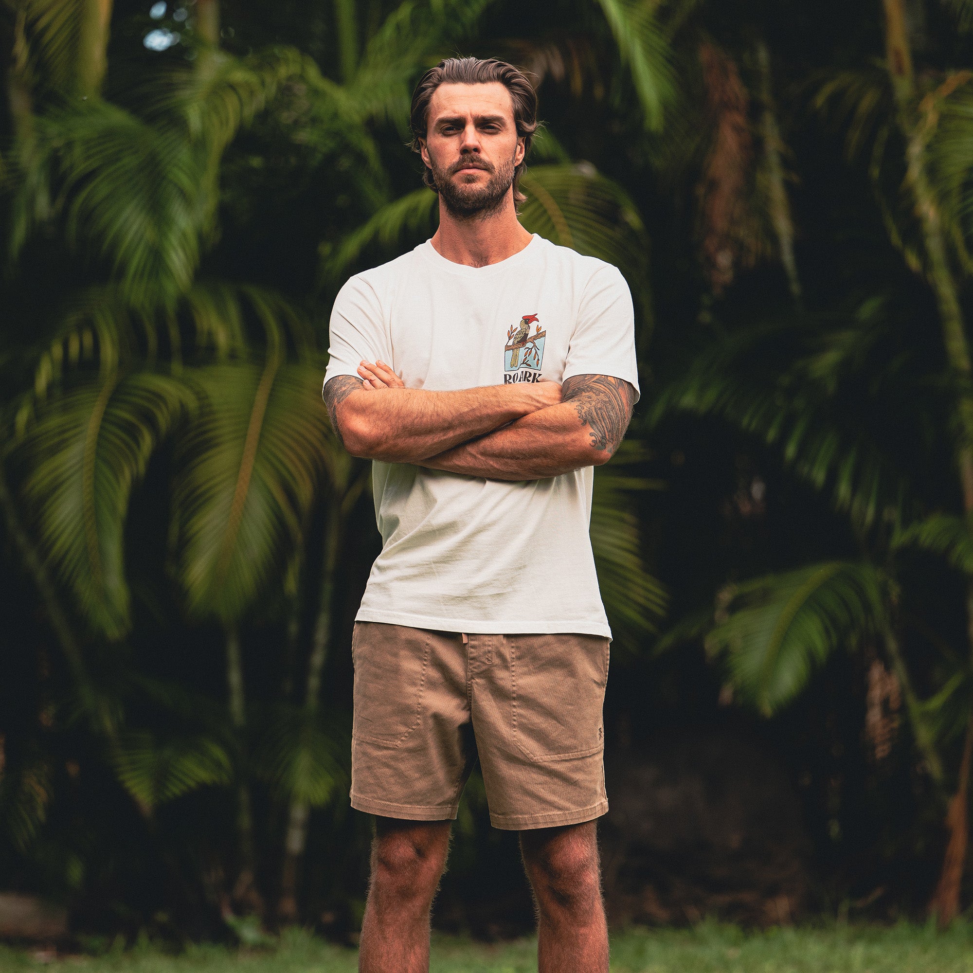Man wearing a premium tee paired with boardshorts, ready for an outdoor adventure by the sea.