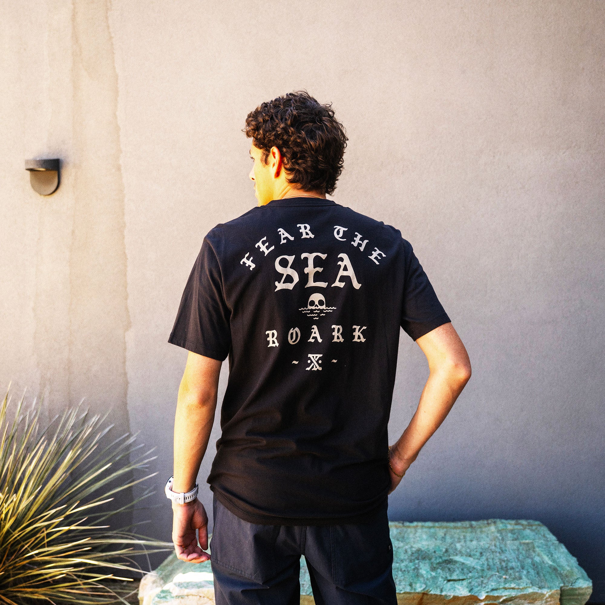 Black Fear The Sea premium t-shirt with white graphic text and skull design on back, worn by male model outdoors
