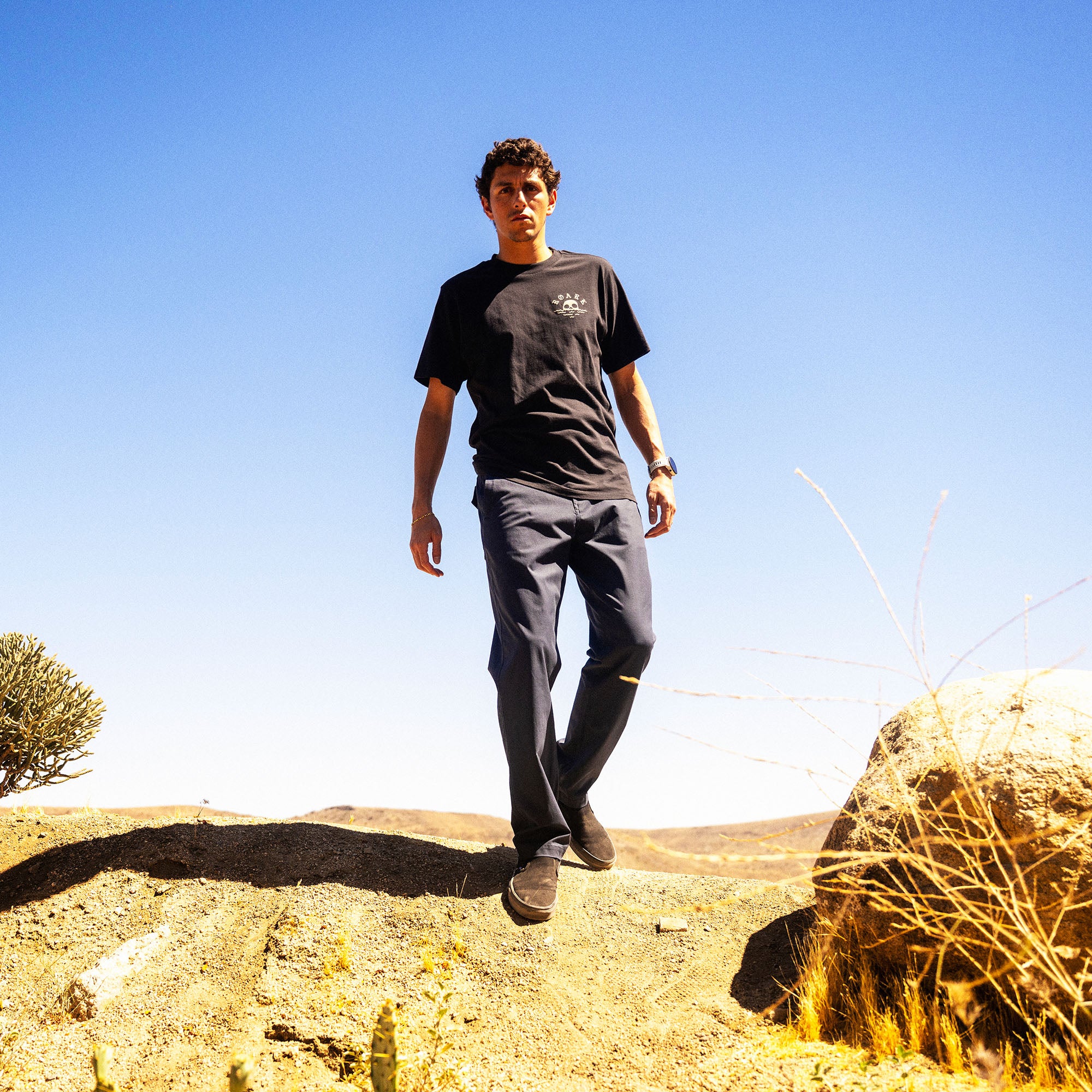 Black Fear The Sea Premium Tee with small skull logo, worn by man standing on desert terrain with clear blue sky