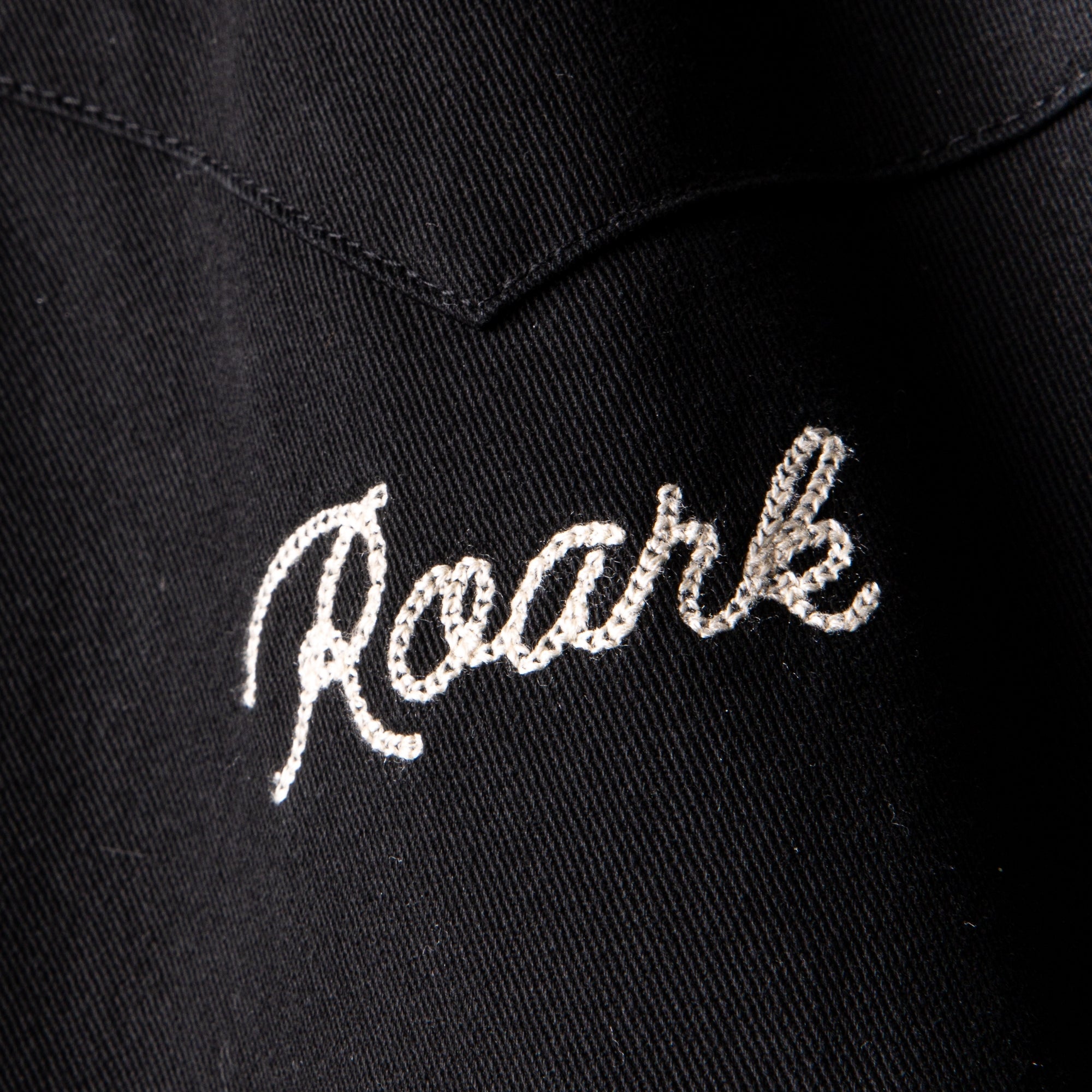 Close-up of the durable Forever Roaming Jacket featuring black and grey textiles with detailed stitching and a distinctive label, perfect for adventure and travel.