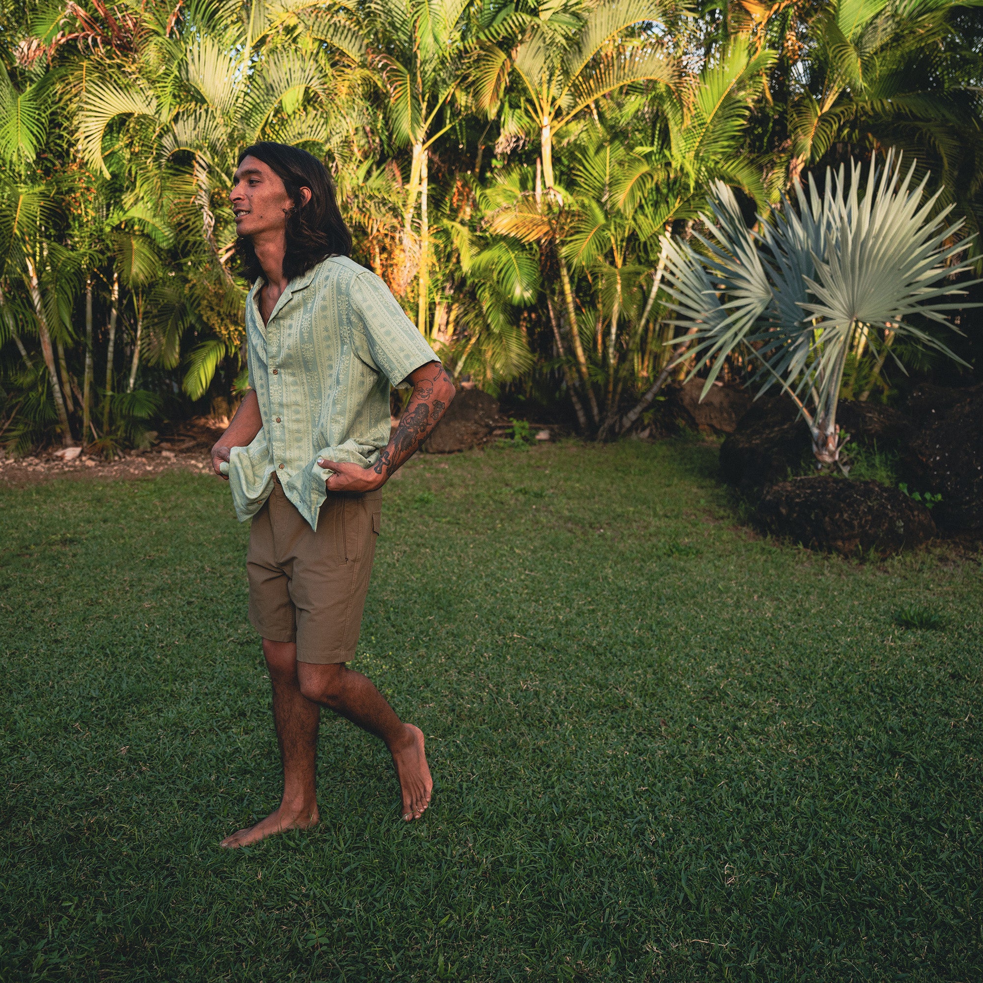 Person sitting leisurely outdoors in summer, wearing Roark's Gonzo Short Sleeve Button Up Shirt, capturing a moment of relaxed adventure.
