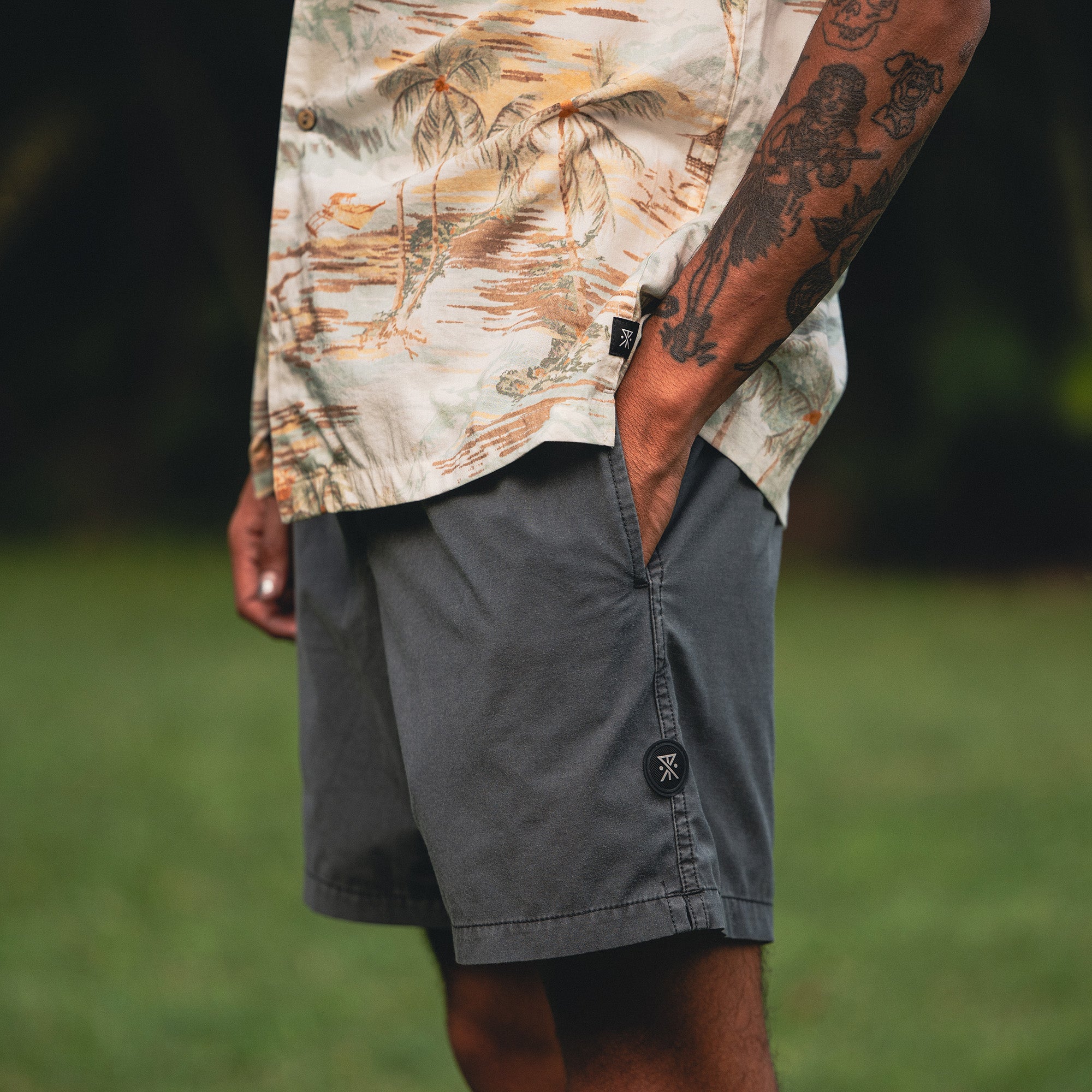 Dog playfully standing next to a person wearing Roark's Gonzo Short Sleeve Button Up Shirt and boardshorts on a sunny beach adventure