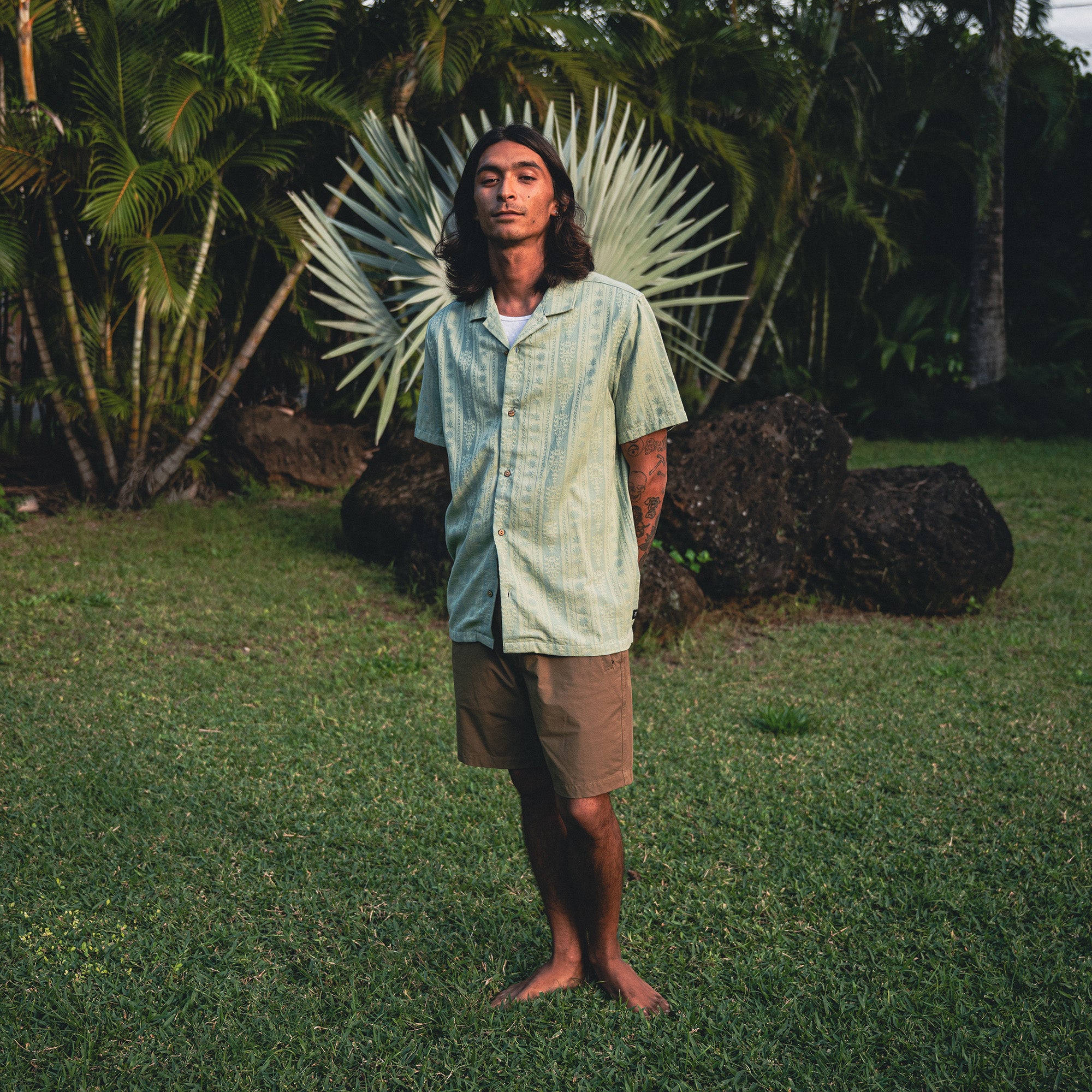 Man wearing a Gonzo Short Sleeve Button Up Shirt and Bermuda shorts enjoying a leisurely day outdoors surrounded by nature.