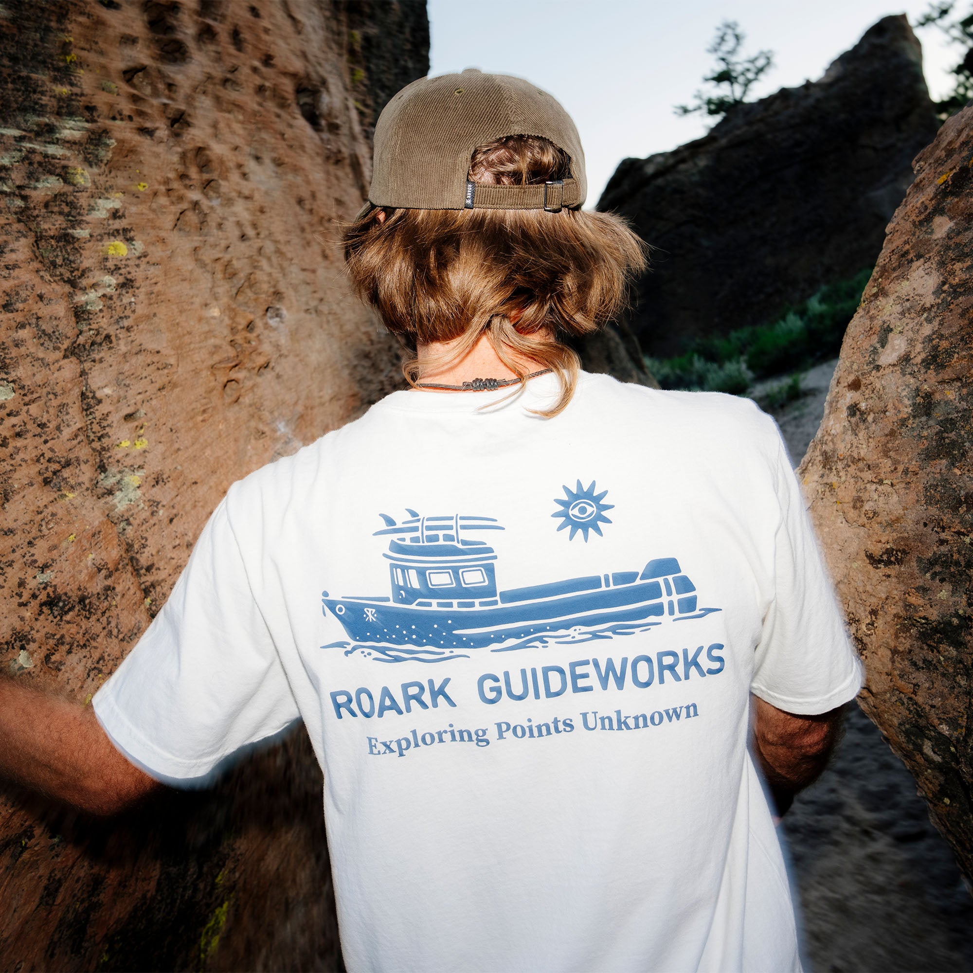 Guideworks Pocket Premium Tee by Roark featuring a subtle logo on active shirt with boat and watercraft in the background, evoking a sense of adventure and travel.