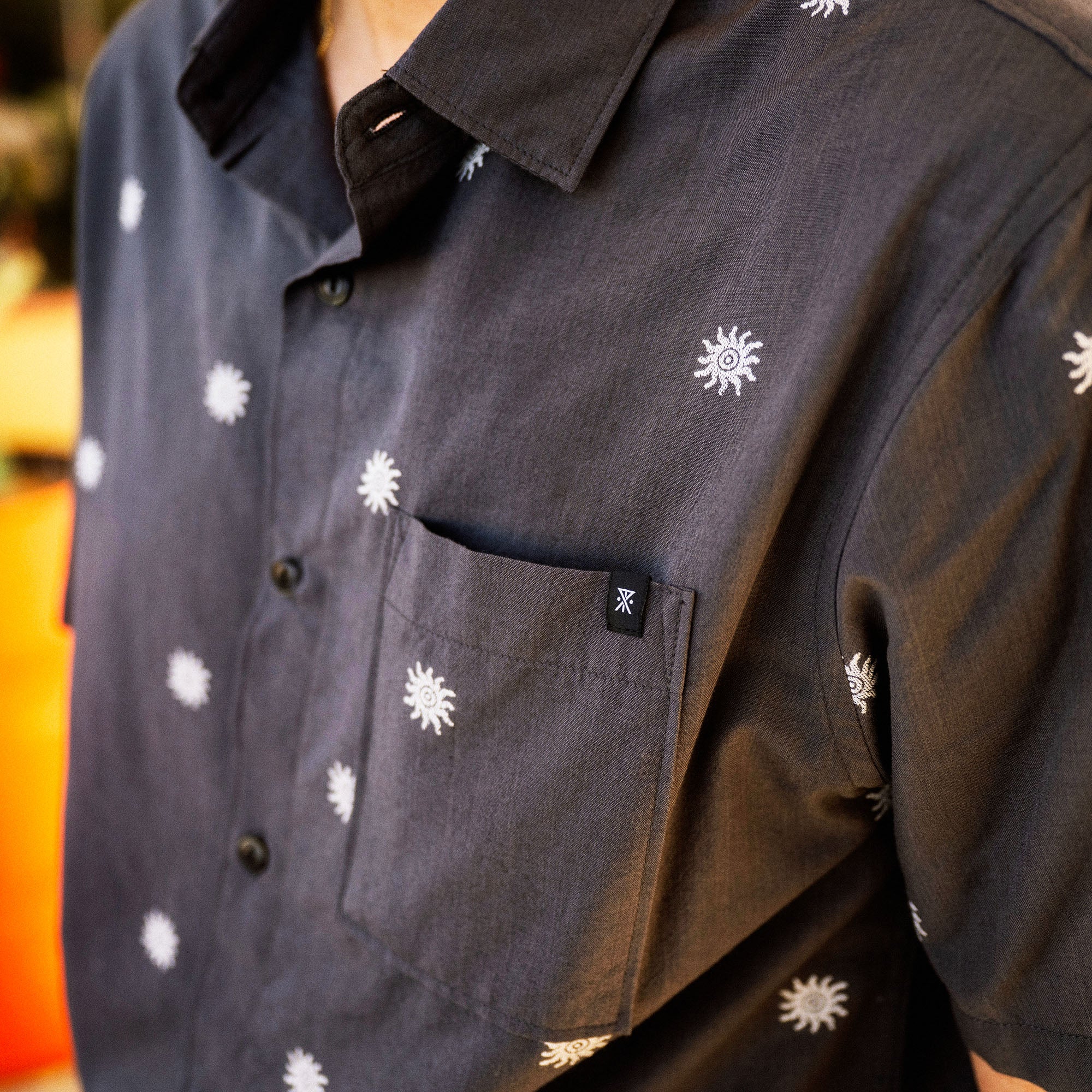 Black button-up shirt with white sun and daisy embroidered motifs throughout the front and sleeves