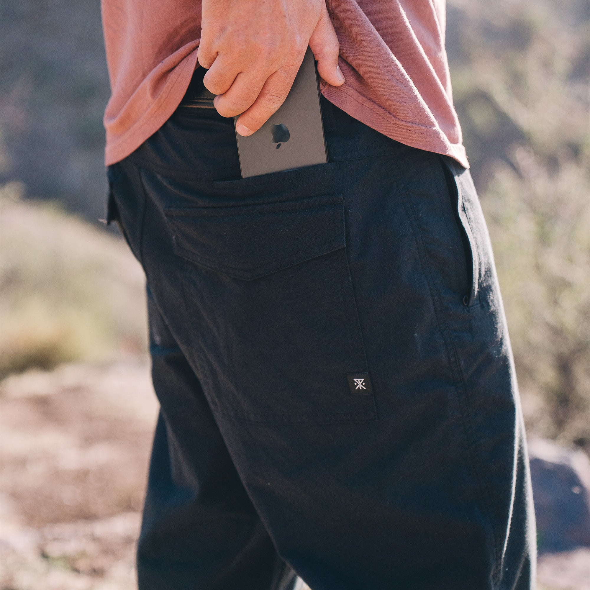 Man adventurously hiking through rugged Bedrock landscape in Layover Pro Pants, ideal for walking and vacation explorations.