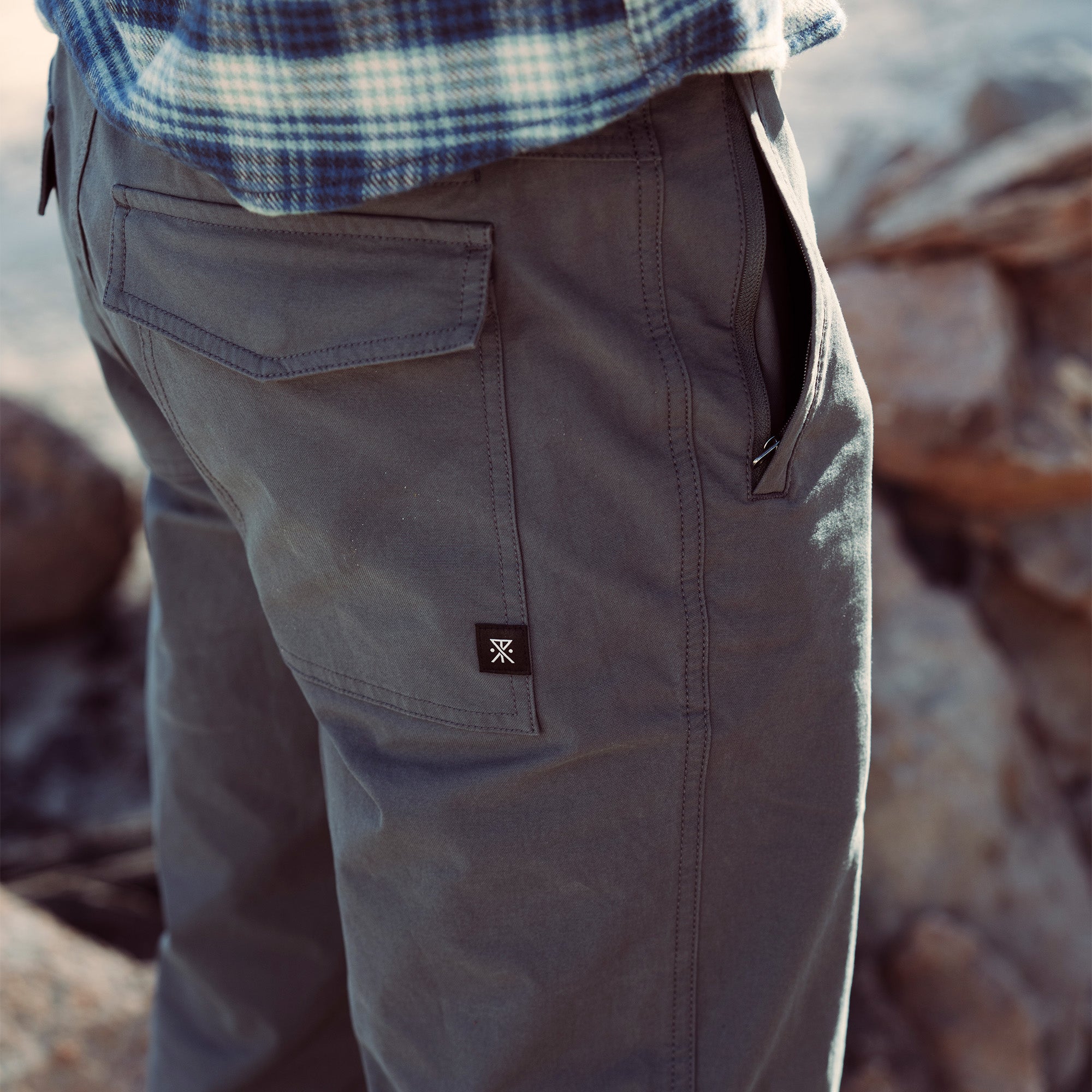 Person hiking on a scenic trail wearing Roark Layover Pro Pants, ideal for adventurous vacations and outdoor explorations.
