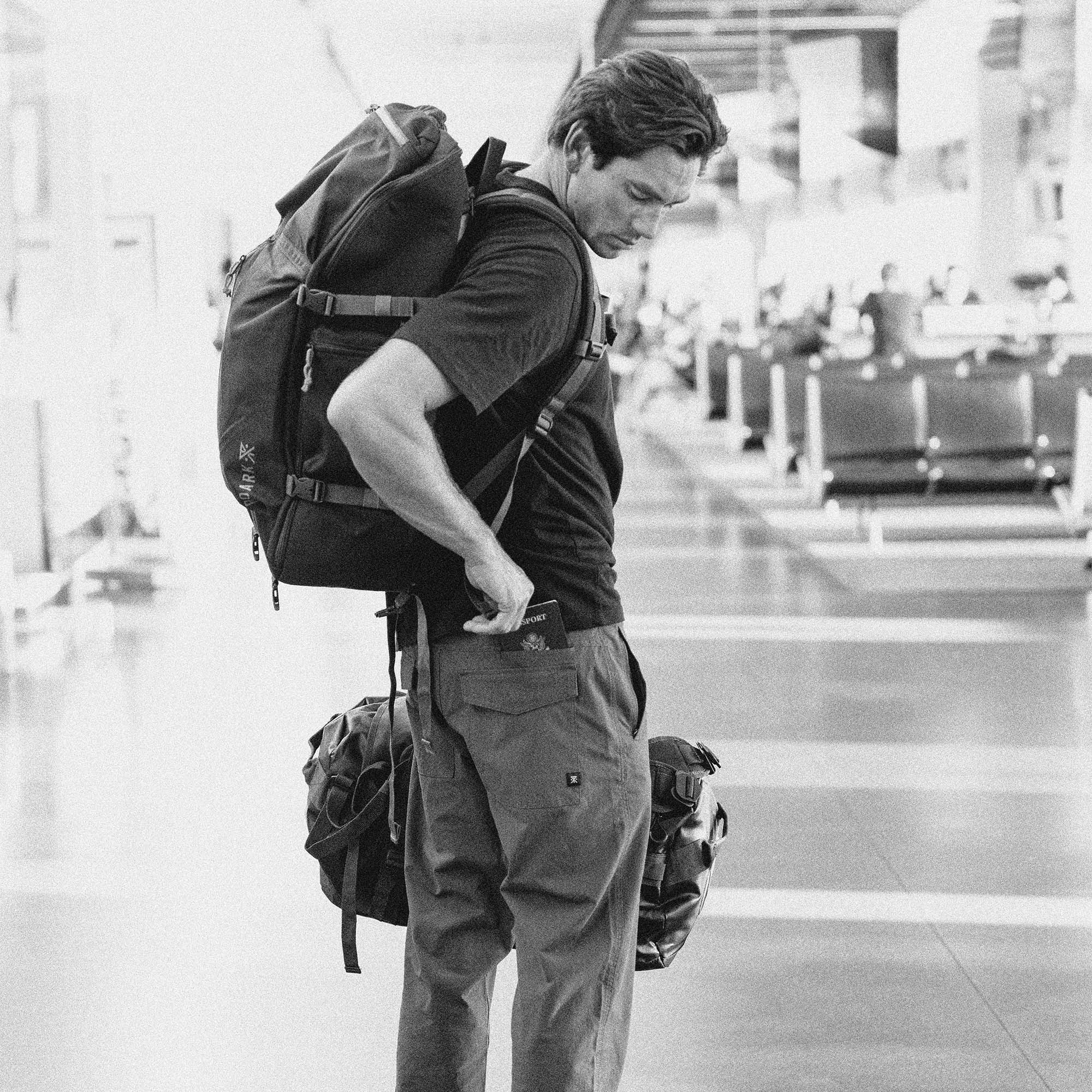 Durable and stylish Layover Pro Pants paired with travel essentials including a backpack and shoes, perfect for adventure and exploration.