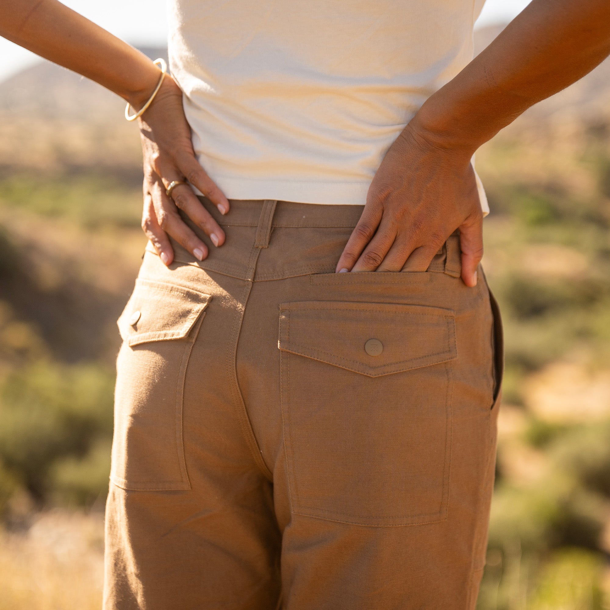 Layover Utility Pants in dark khaki worn on model outdoors, showing back view with cargo pockets and relaxed fit