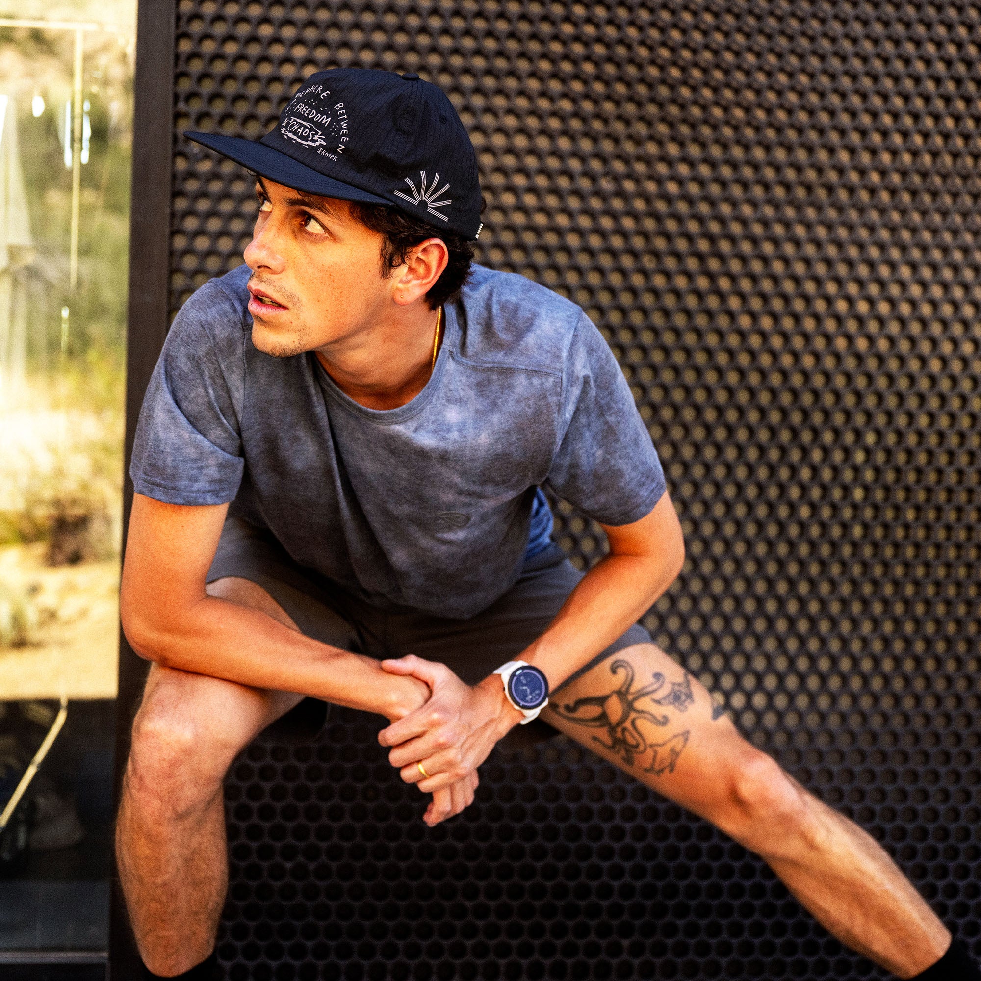 Man wearing dark slate blue short-sleeve tee with navy baseball cap in active lifestyle setting during outdoor workout