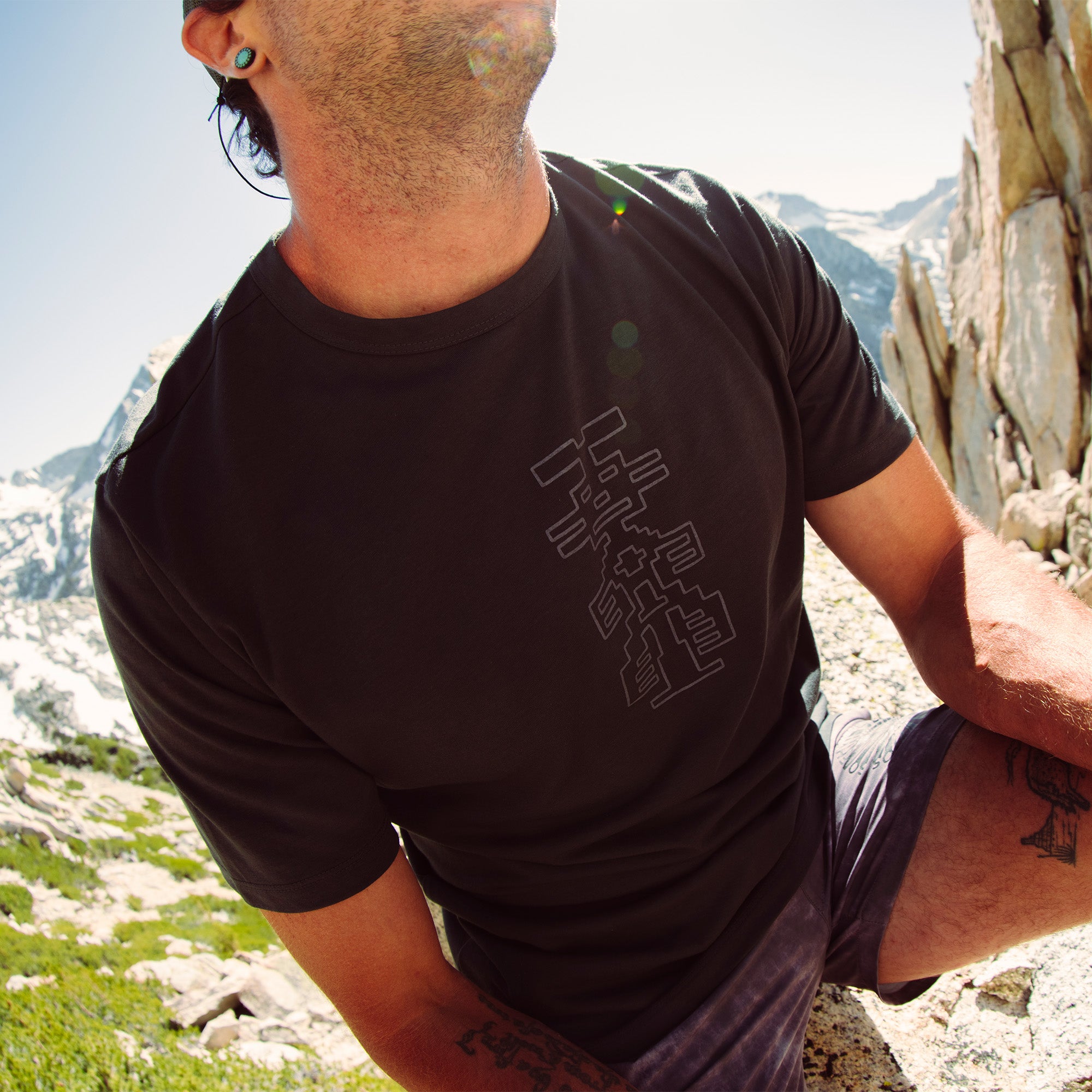 Man standing confidently in a Roark Mathis Active Short Sleeve Tee, designed for adventure and travel, showcasing the fit and style as he enjoys the outdoors.