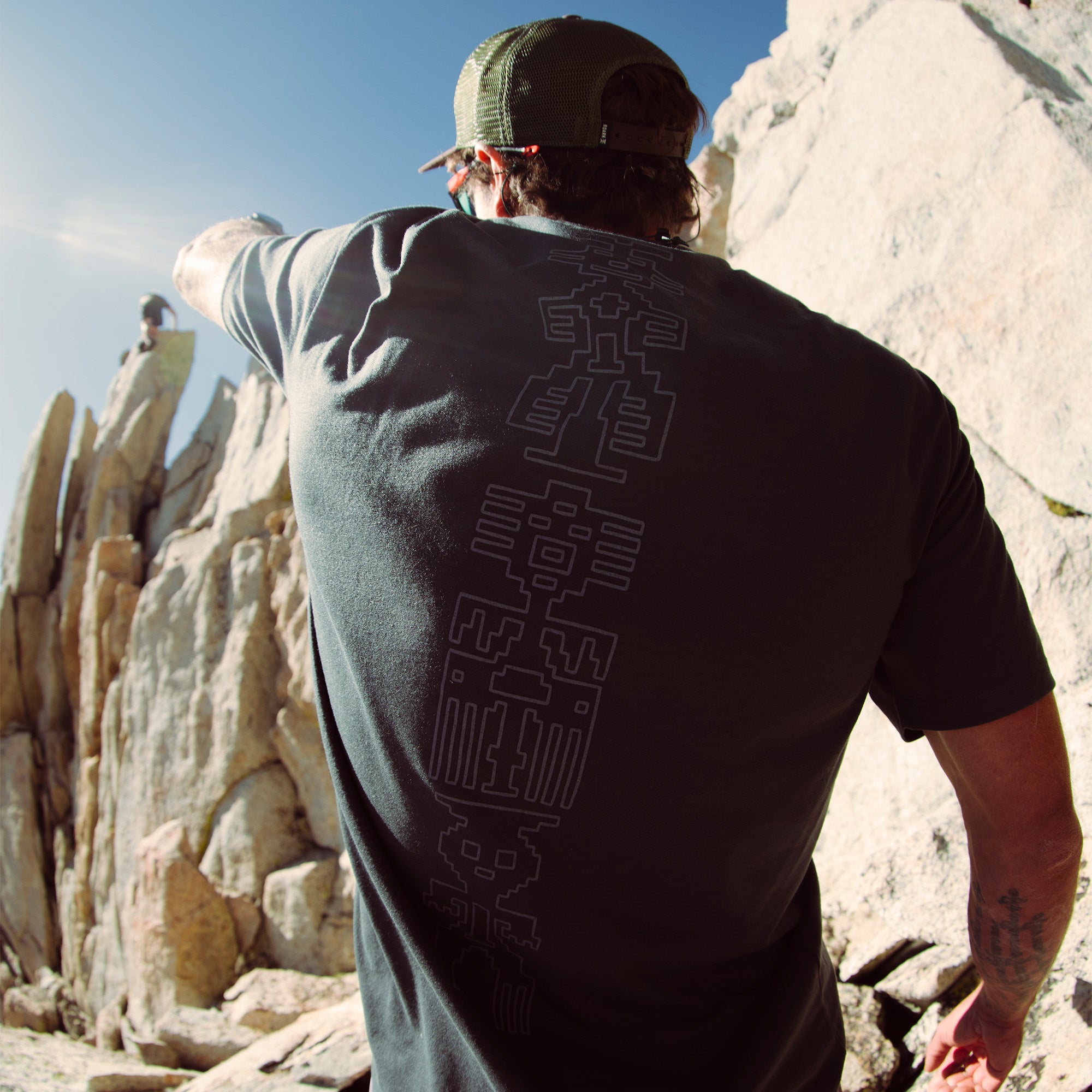 Active outdoor enthusiast wearing a Mathis Short Sleeve Tee and baseball cap, standing on a ridge, embodying Roark's spirit of adventure and travel.