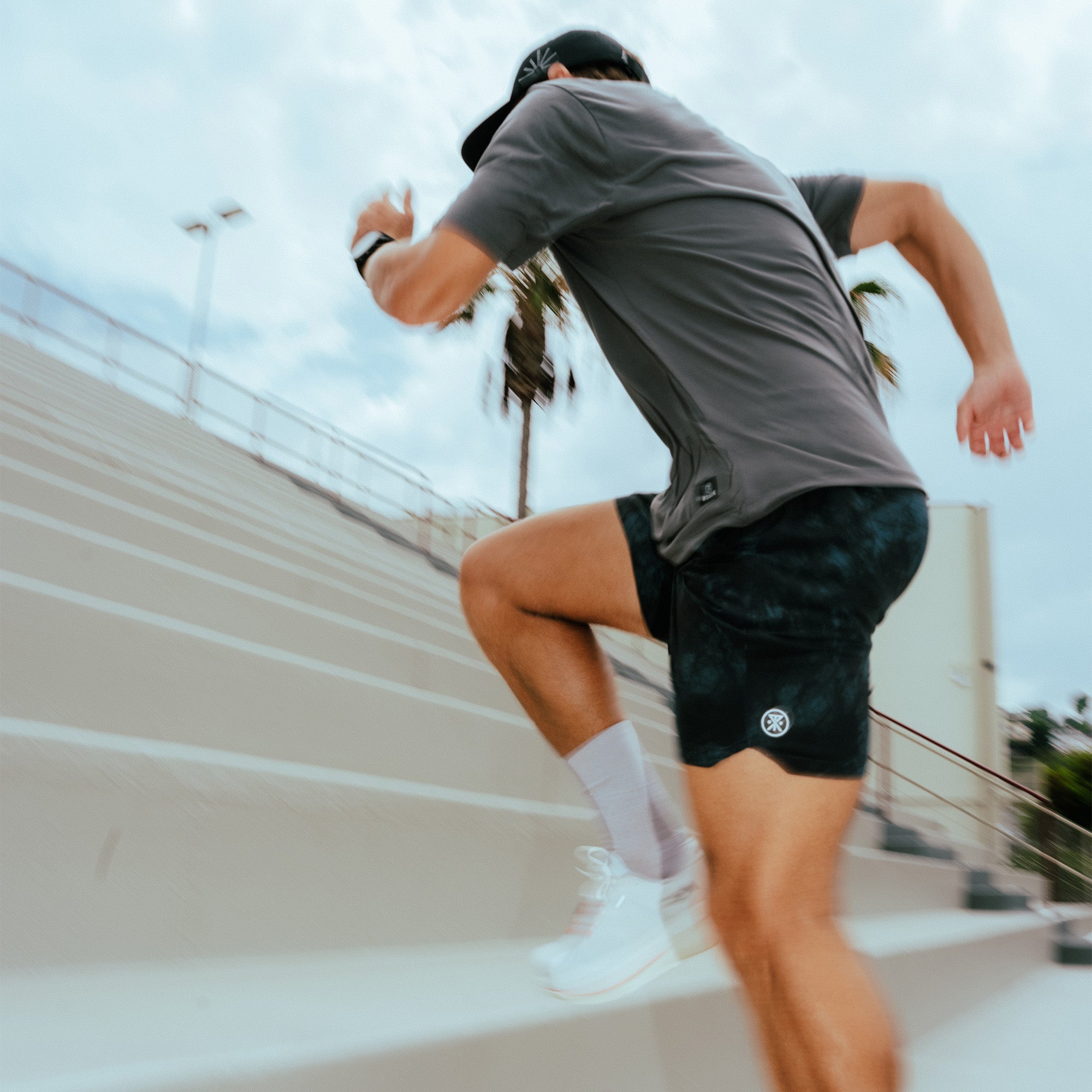Person running outdoors wearing gray active short-sleeve tee and black shorts with white socks