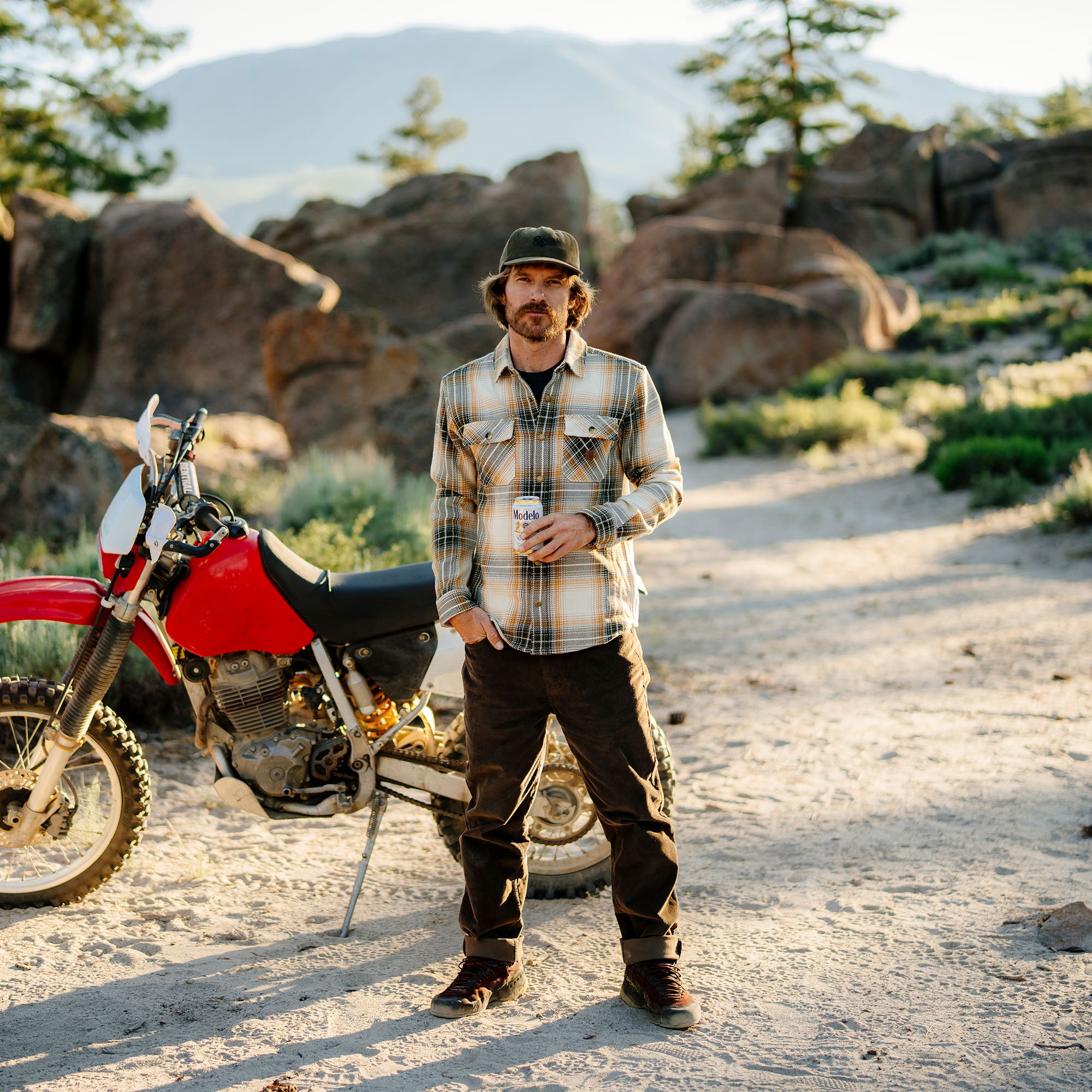 Adventurous person wearing a variety of travel gear including a hat, sunglasses, and goggles, ready for an outdoor expedition