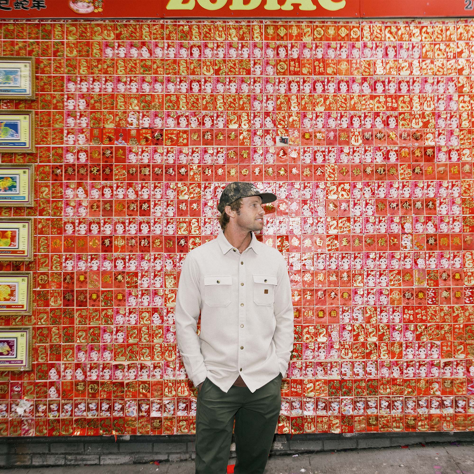 Close-up of a vibrant orange Nordsman Long Sleeve Flannel by Roark, featuring the distinctive Roark logo, ideal for outdoor adventures and travel.