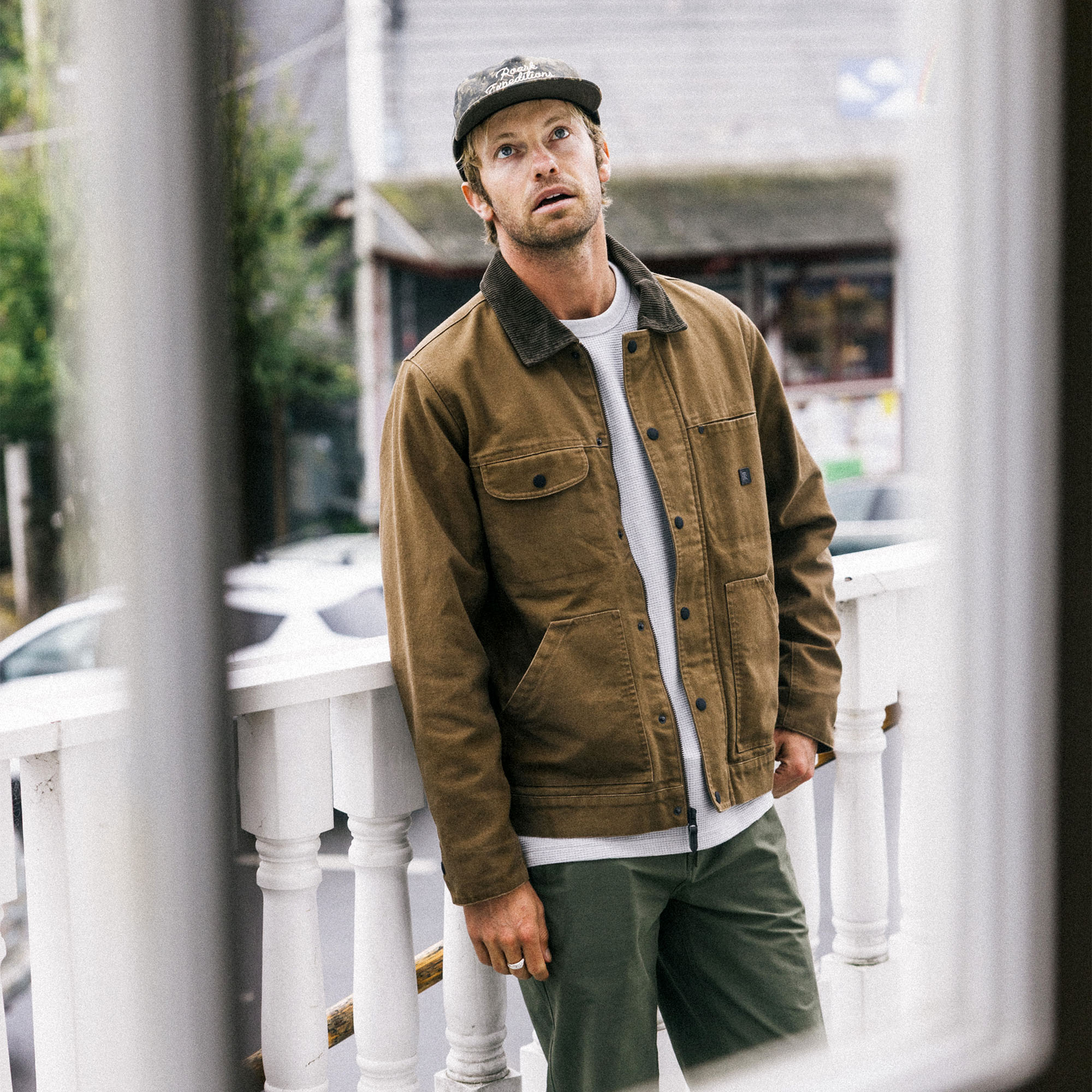 Adventure-ready waxed canvas jacket by Roark, displayed on an open road trip with a rugged sport utility vehicle in a scenic setting.