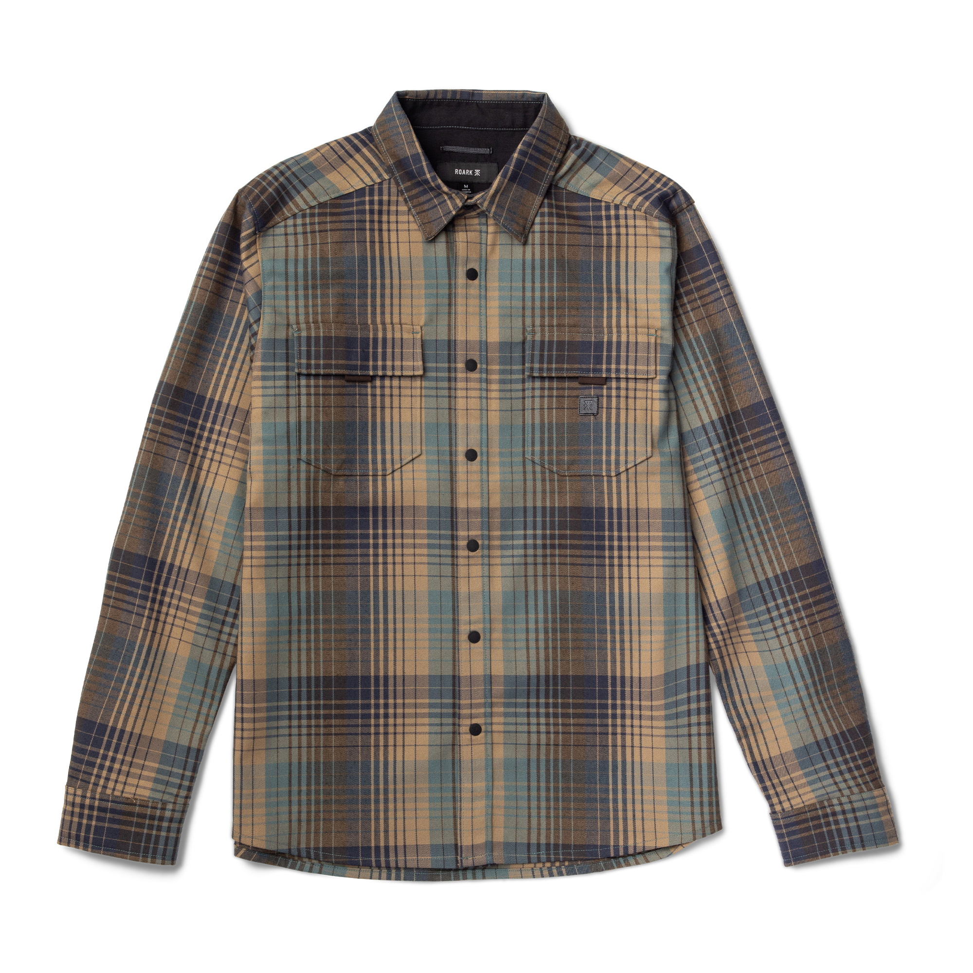 Man in Roark khaki adventure pants exploring a scenic outdoor trail surrounded by lush greenery.