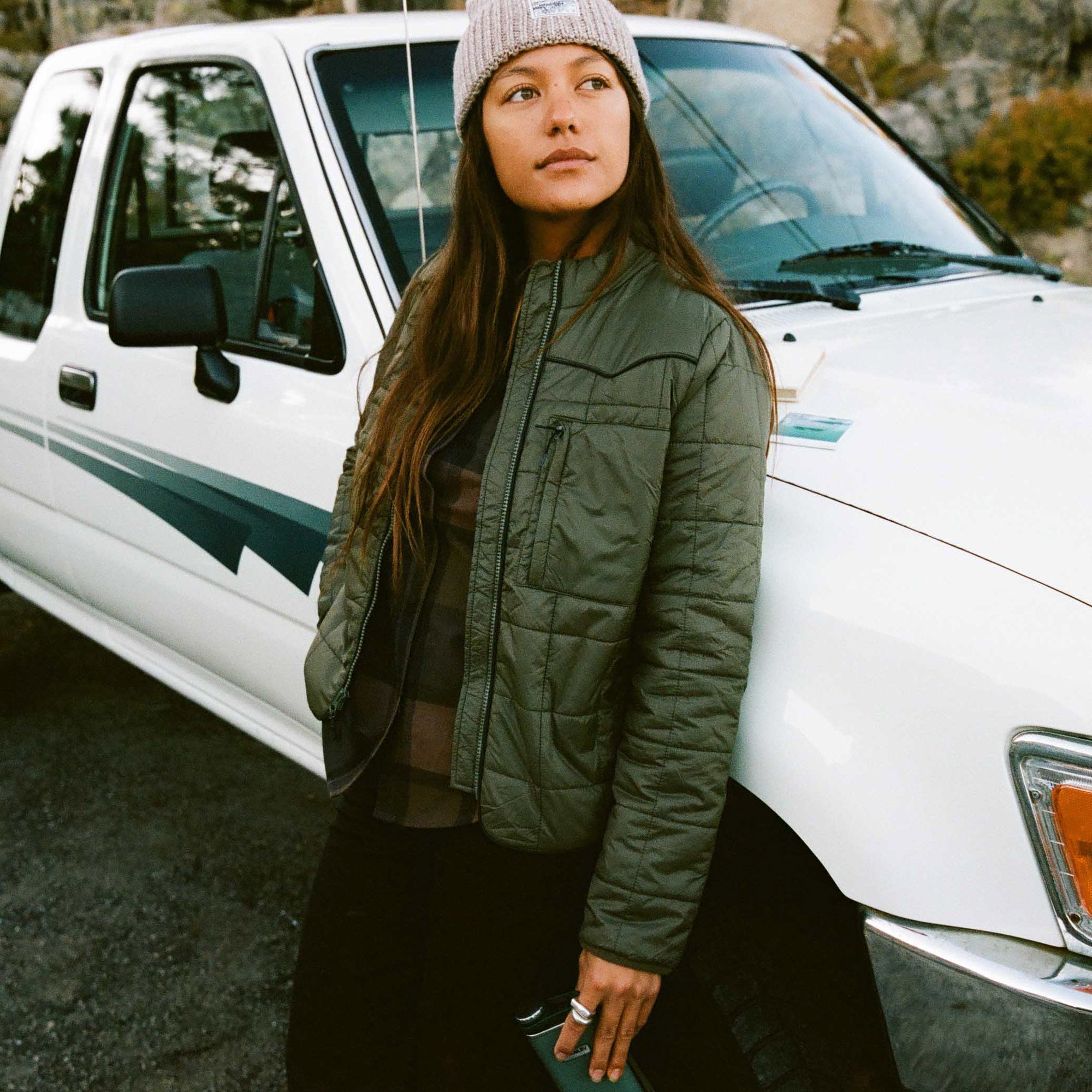 Stylish adventurer dressed in a cozy jacket and knit cap embracing the winter season, representing Roark's commitment to outdoor and travel-inspired lifestyle.