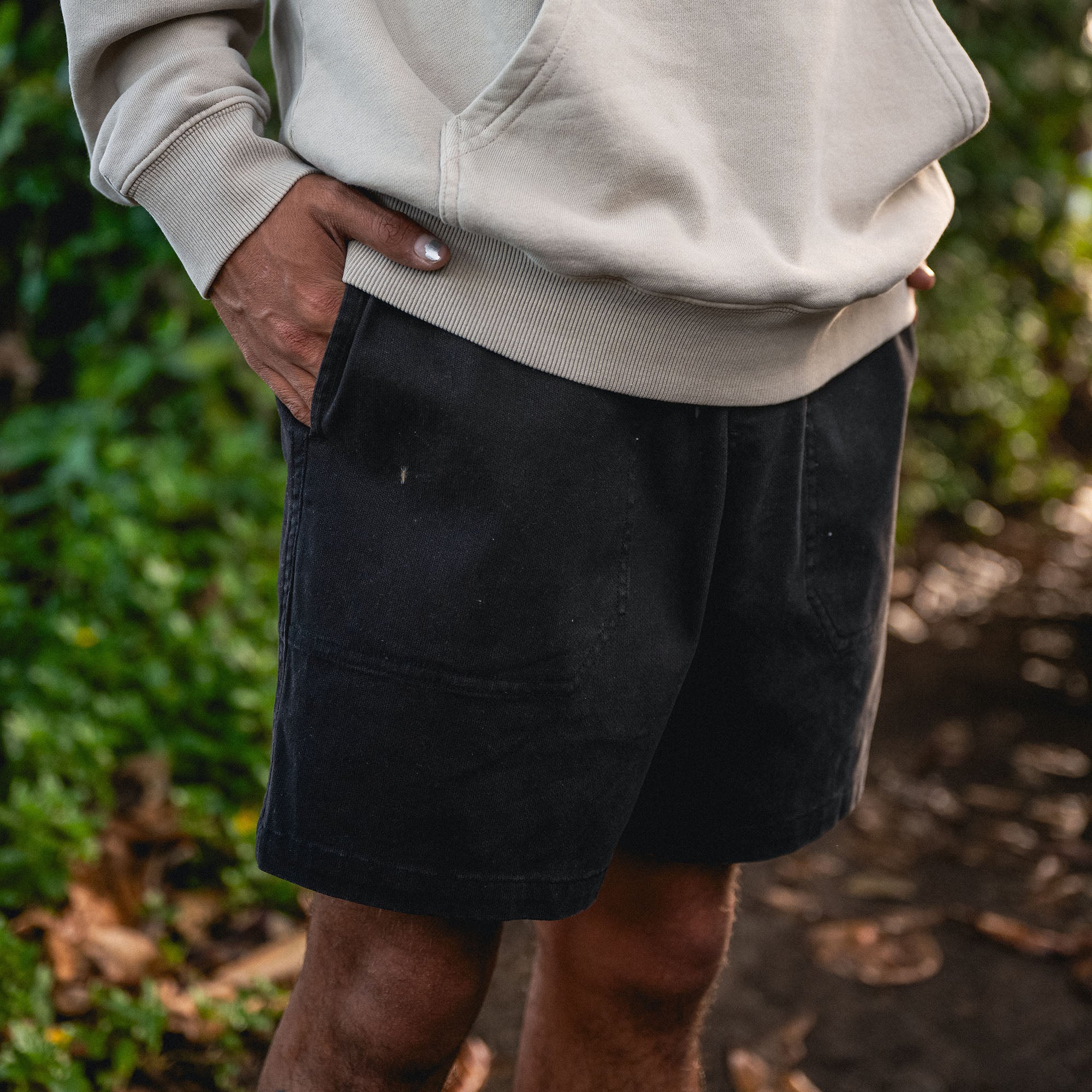 Model wearing Roark's adventure-ready shorts, showcasing Safe Camp Embroidery on fleece, surrounded by lush outdoor scenery.