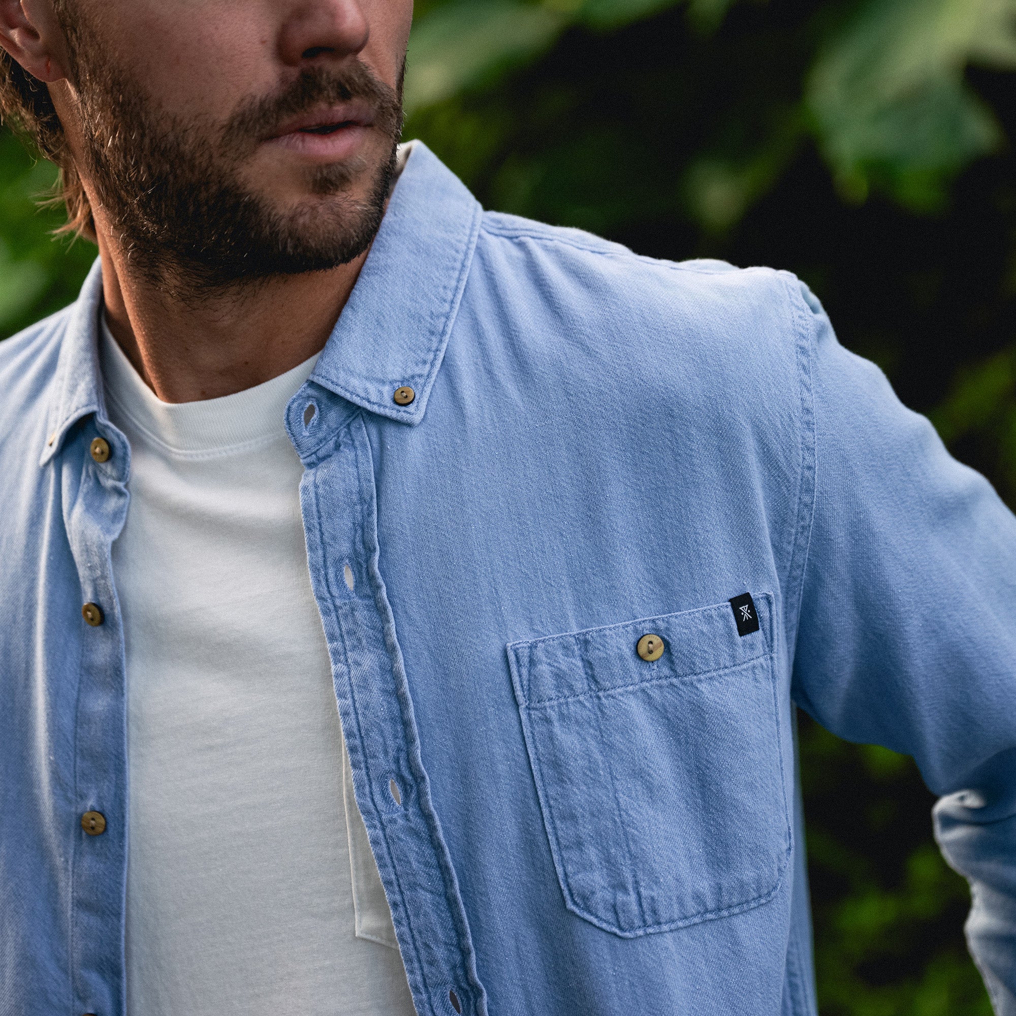 Close-up of a Scholar Chambray button-up shirt featuring detailed stitching on buttons and pockets, perfect for adventure and travel.