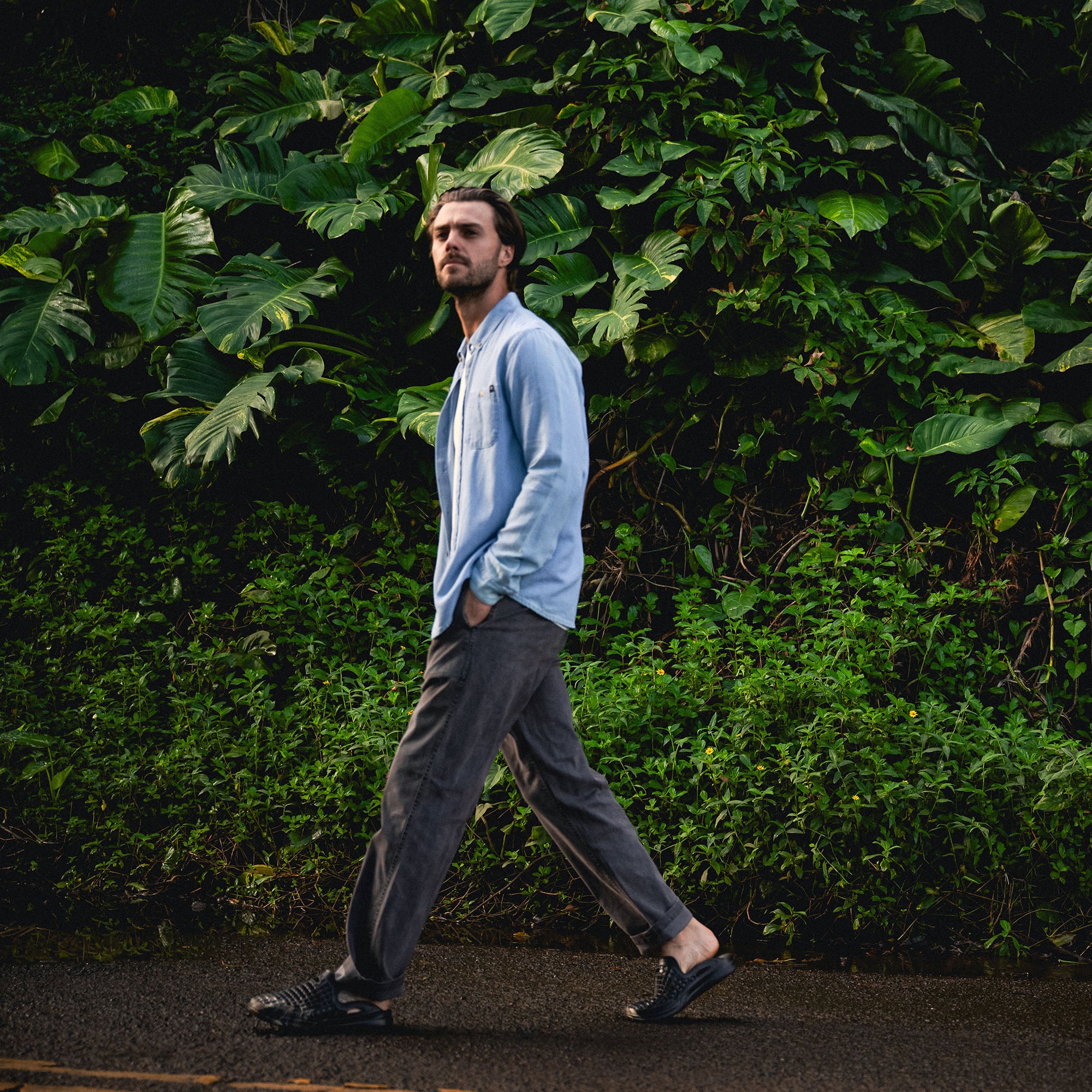 Adventurous individual exploring nature while wearing Roark's Scholar Chambray Button-Up Shirt, showcasing stylish details like the collar and sleeves.