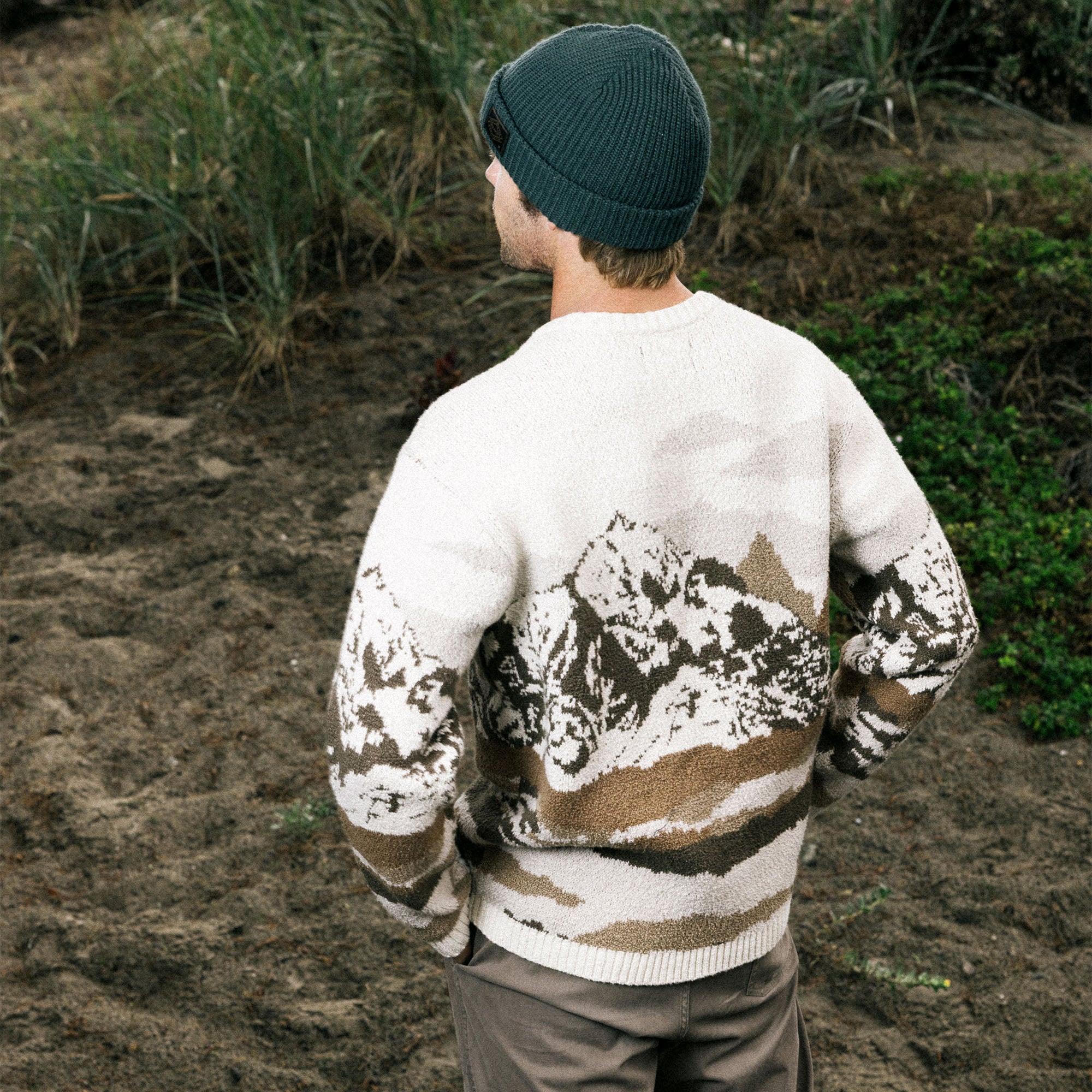 Winter adventurer wearing a camouflage long sleeve wool sweater by Roark, blending into a snowy landscape