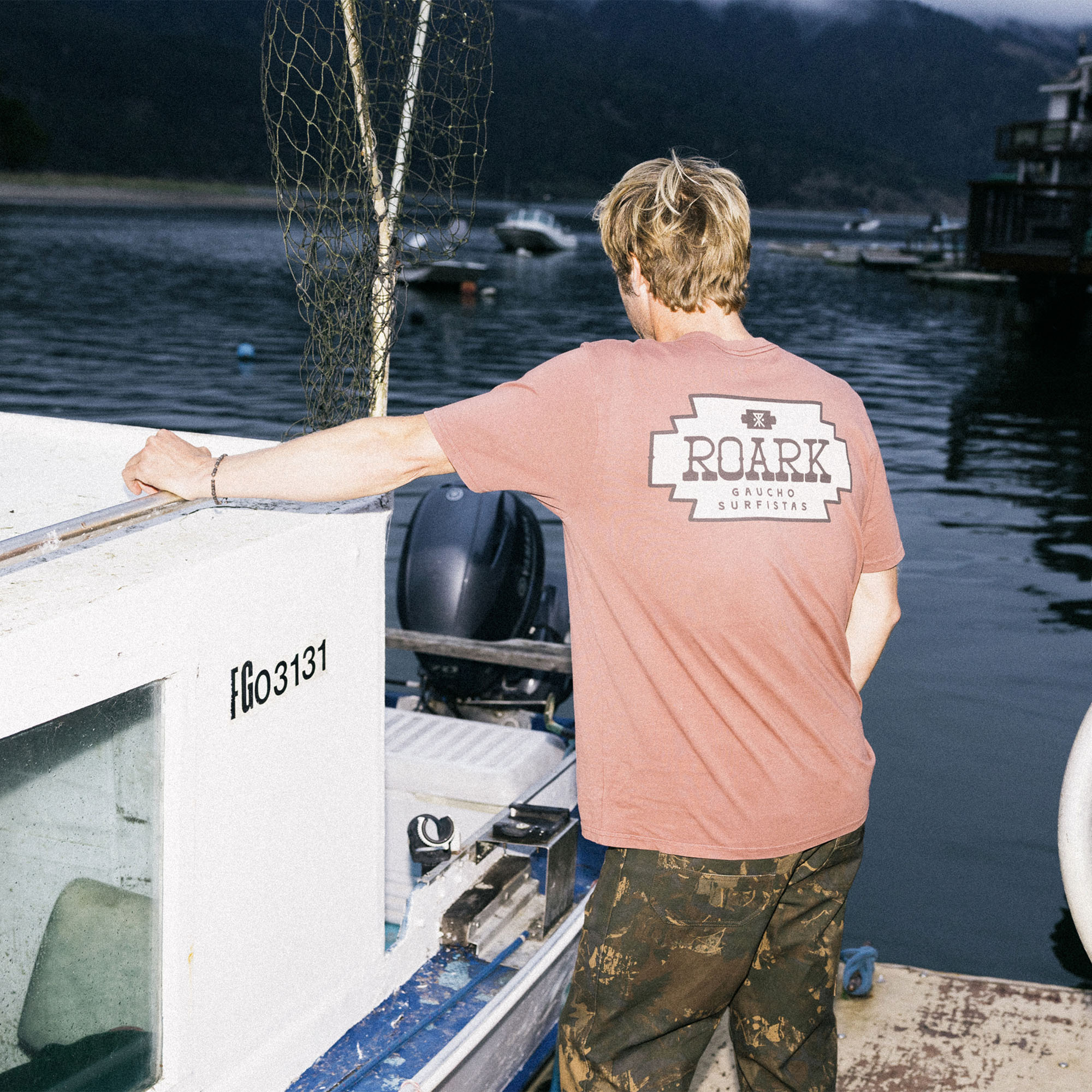 Man in active shirt and cap enjoying a boat ride, embodying Roark's spirit of adventure and travel on the water