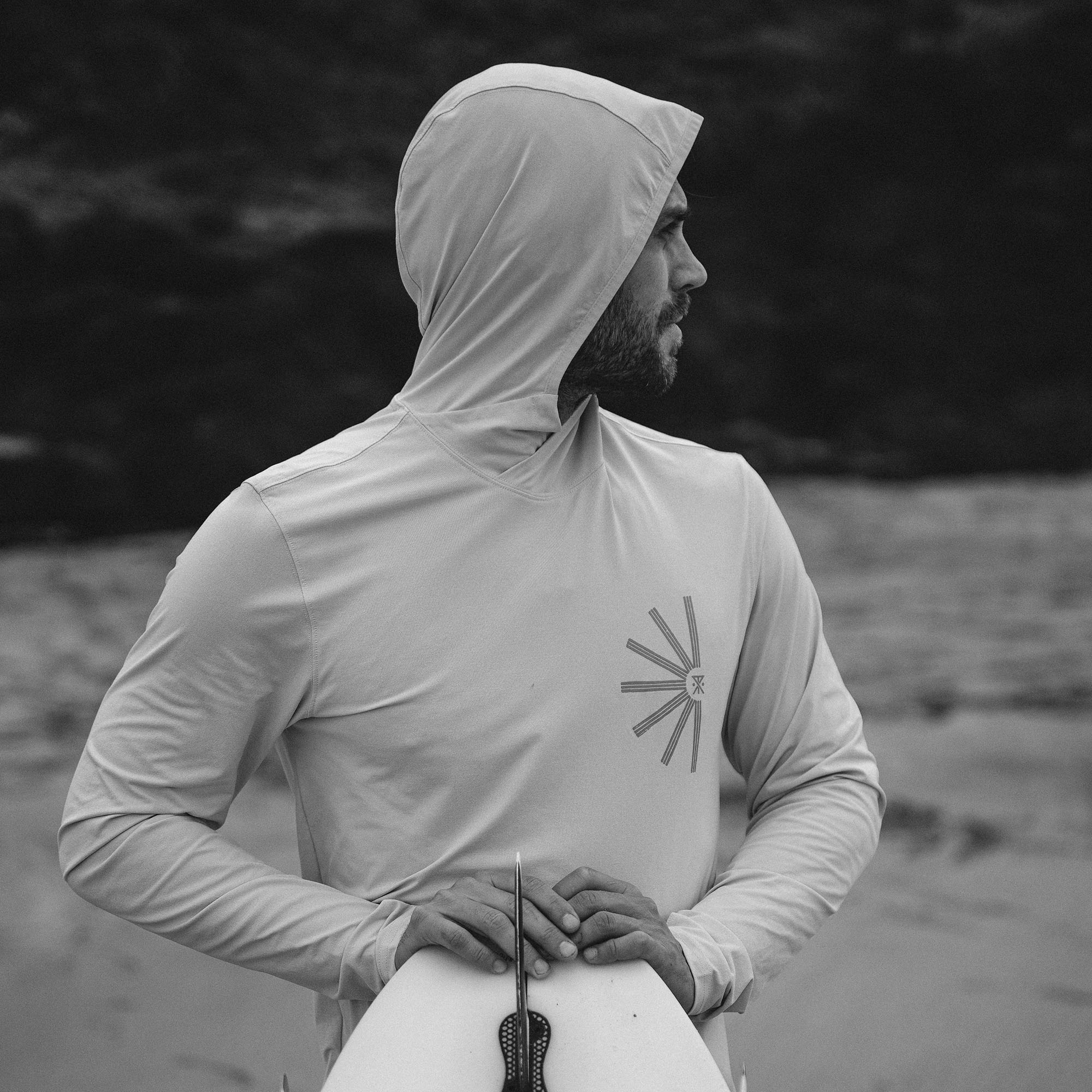 Man with a beard wearing Roark Venture UPF Hoodie in an outdoor setting, showcasing long sleeves and hood for optimal sun protection.