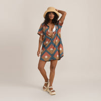 Summer fashion: Woman in a patterned short dress with a straw hat and white chunky sandals.