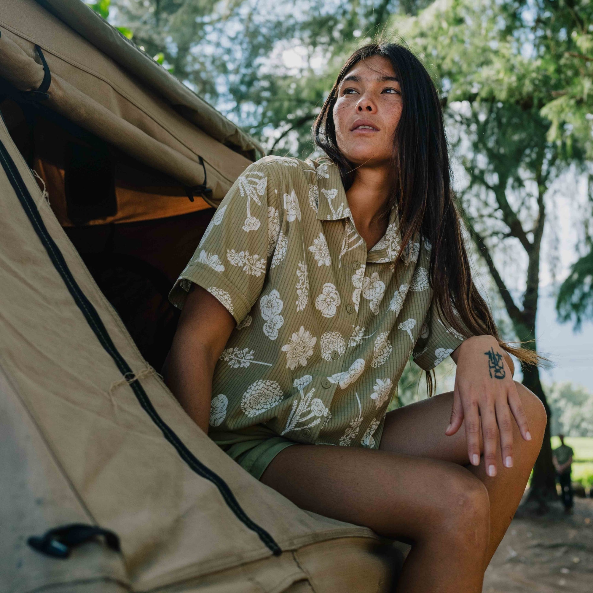 Fashion model wearing a military camouflage shirt with a distinctive collar, styled for adventure and outdoor travel, part of Roark's women's collection.